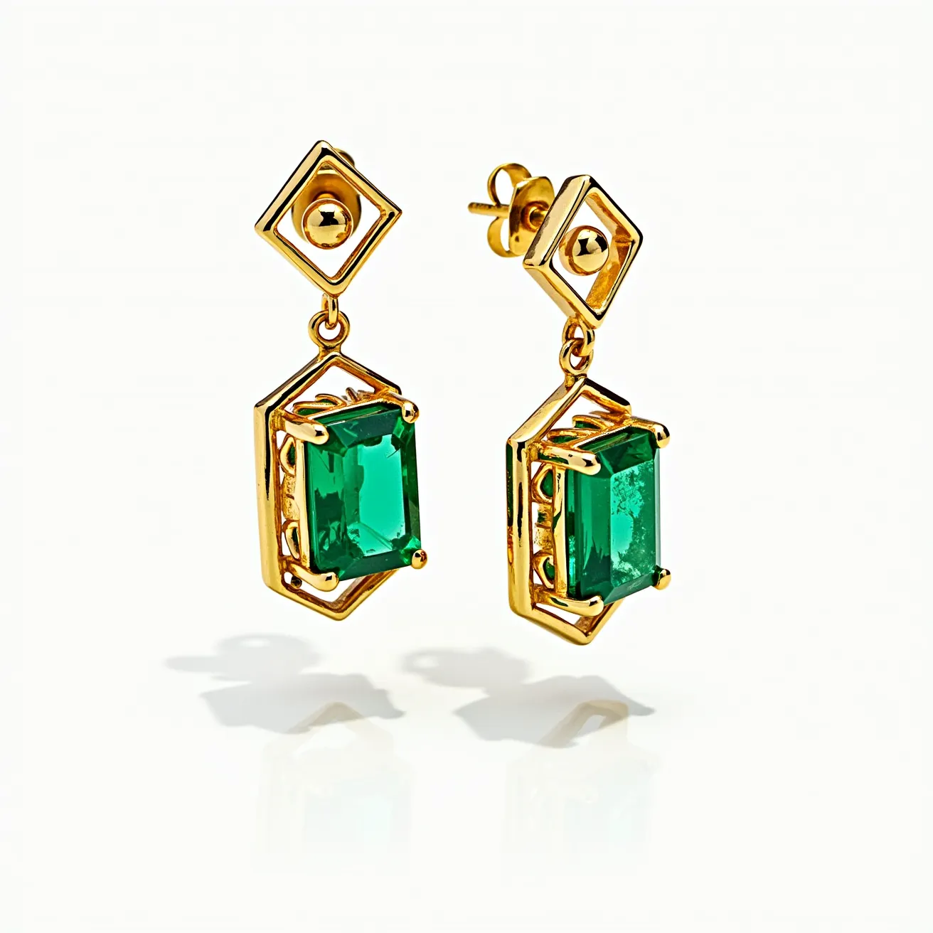 These emerald earrings feature a striking design with prominent rectangular-cut emerald stones, set in a luxurious gold framework. The emeralds are beautifully showcased in an elegant prong setting that securely holds the stones while allowing maximum light to amplify their vibrant green hue. The earrings are suspended from a geometric motif, which appears to be a hollow square linked to the main stone setting, creating a modern and sophisticated aesthetic. They attach to the ear via a classic post and butterfly clutch, ensuring they remain comfortably in place when worn. The combination of exquisite emeralds and the warmth of gold results in a timeless yet contemporary pair of earrings.