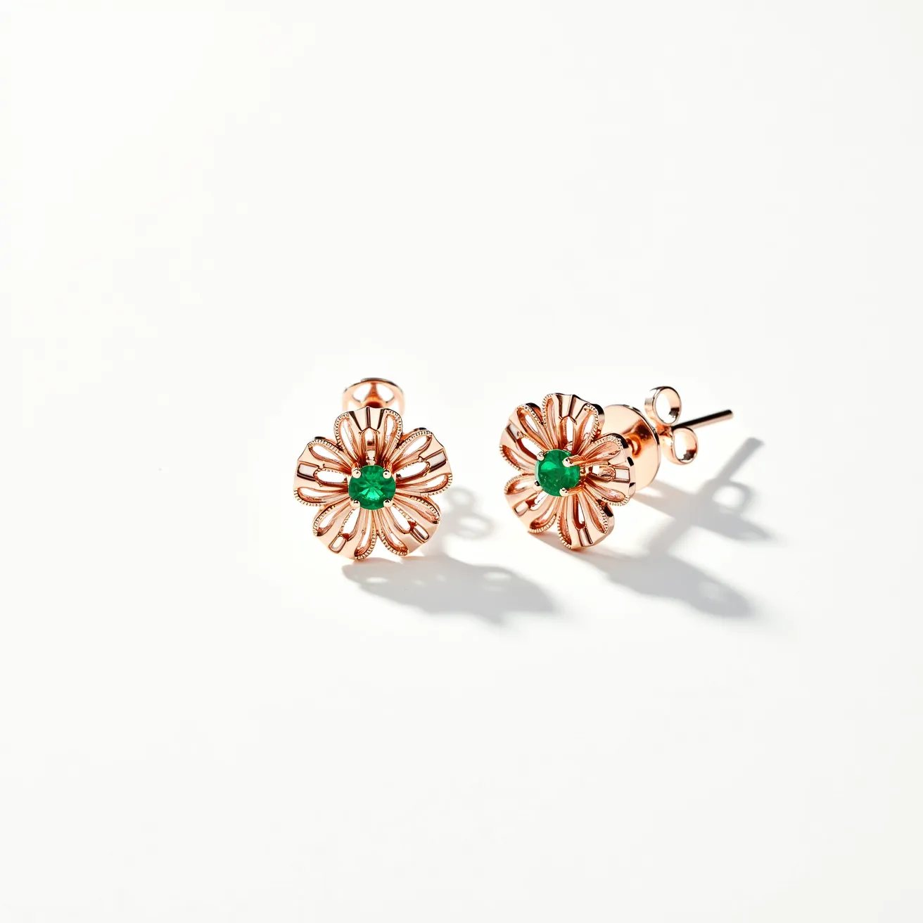 These floral earrings feature an elegant design crafted from rose gold, forming intricate petals that create a beautiful flower motif. At the center of each earring is a striking round-cut green gemstone, possibly an emerald, securely set in a bezel setting that adds a touch of sophistication and color contrast. The earrings are equipped with a post and butterfly clasp, ensuring a secure and comfortable fit for the wearer. The combination of the warm hue of rose gold and the vibrant green centerpiece gives these earrings a timeless and versatile appeal.