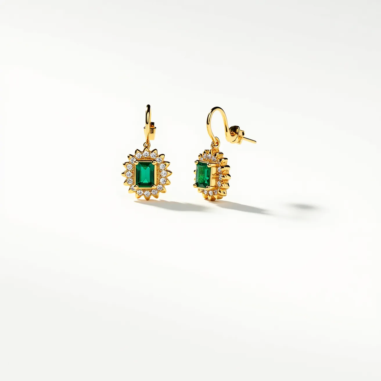 These floral earrings are elegantly designed with a central green emerald-cut gemstone, which is the focal point of the piece. Surrounding the central gem are numerous small, round white stones, likely diamonds, arranged in a halo that enhances the floral motif. The stones are set in a yellow gold metal, providing a rich and warm backdrop that accentuates the vibrant green of the central stone. The earrings feature lever-back clasps, ensuring they remain securely in place while worn. The combination of the green gemstone, sparkling white stones, and gold setting creates a classic and luxurious appearance.