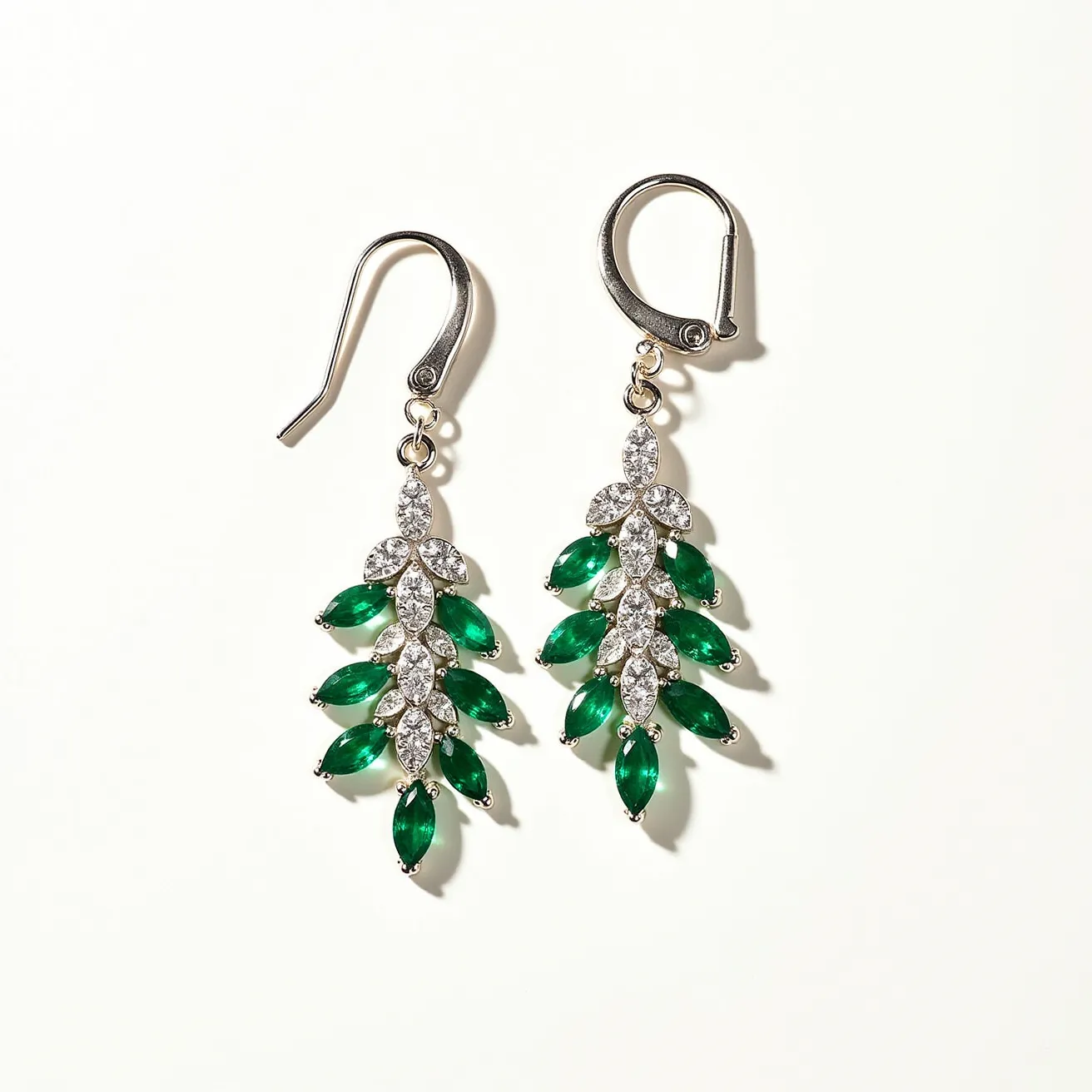 These floral earrings feature a captivating design with both clear and green stones, suggesting a combination of synthetic or natural materials. The green gems are meticulously arranged in a marquise cut, resembling leaves, while the clear stones are round cut and set in a manner that mimics blooming flowers. The structure is held together by a shiny metal that appears to be either silver or a silver-toned alloy, highlighting the vibrant contrast and elegance of the design. The attachment includes a fish hook clasp on one earring and a lever-back clasp on the other, offering secure and comfortable wear. The gemstones are securely mounted, suggesting a prong or bezel setting that complements the intricate floral pattern.