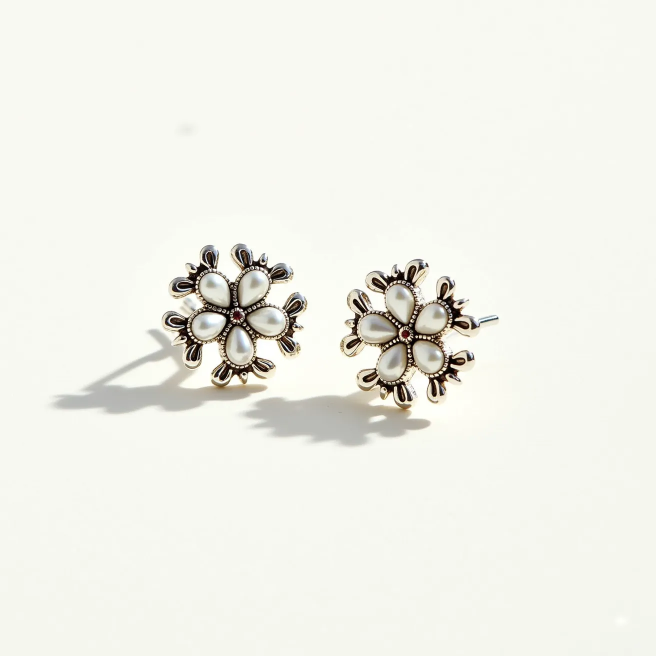 These floral stud earrings feature an elegant design with petal-like shapes composed of smooth, white materials resembling mother-of-pearl or enamel inlays. Each earring showcases six petals arranged around a central, tiny gemstone that may be a clear or subtle rhinestone embellishment. The petals are bordered by a delicate metallic setting, possibly gold or gold-tone, enhancing their floral appearance. These earrings utilize a traditional stud post for attachment, suitable for pierced ears, providing both a secure and comfortable fit. The overall design captures a vintage-inspired aesthetic with its intricate details and elegant composition.