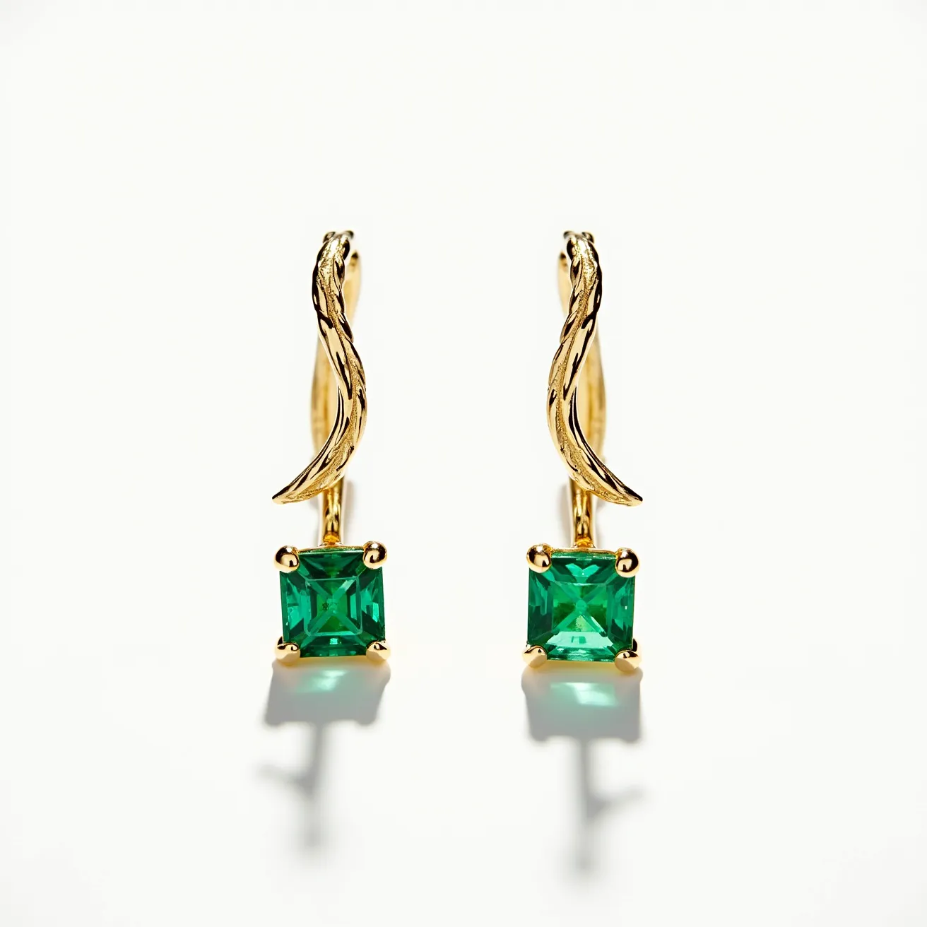 These gold cartilage earrings exhibit a sophisticated design with a graceful twist in their gold framework, made from a lustrous yellow gold. The focal point of each earring is a vibrant green gemstone, cut into a precise square shape, and secured within a classic four-prong setting. The elegant stones are likely emeralds given their deep green hue, adding a touch of luxury to the overall design. The earrings feature a hook clasp, providing secure attachment while enhancing the refined aesthetic.