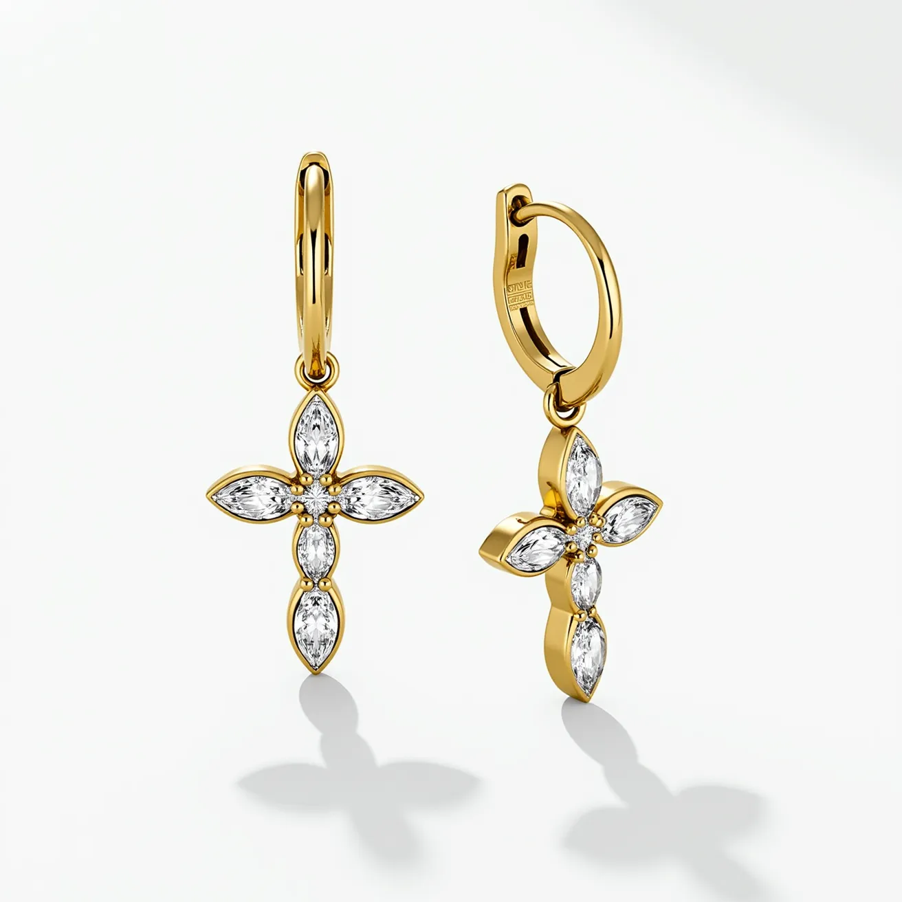 These gold cross earrings feature a classic design with a polished gold finish. Each earring is adorned with four marquise-cut gems that are set in a floral pattern to form the cross shape, giving them a sophisticated and elegant appearance. The gems are securely set in a bezel setting, enhancing the luxurious look. The earrings are attached to small gold hoops with a hinged clasp, providing both a secure and comfortable fit. The combination of the gold material and the shimmering stones creates a striking contrast, making these earrings a timeless accessory.