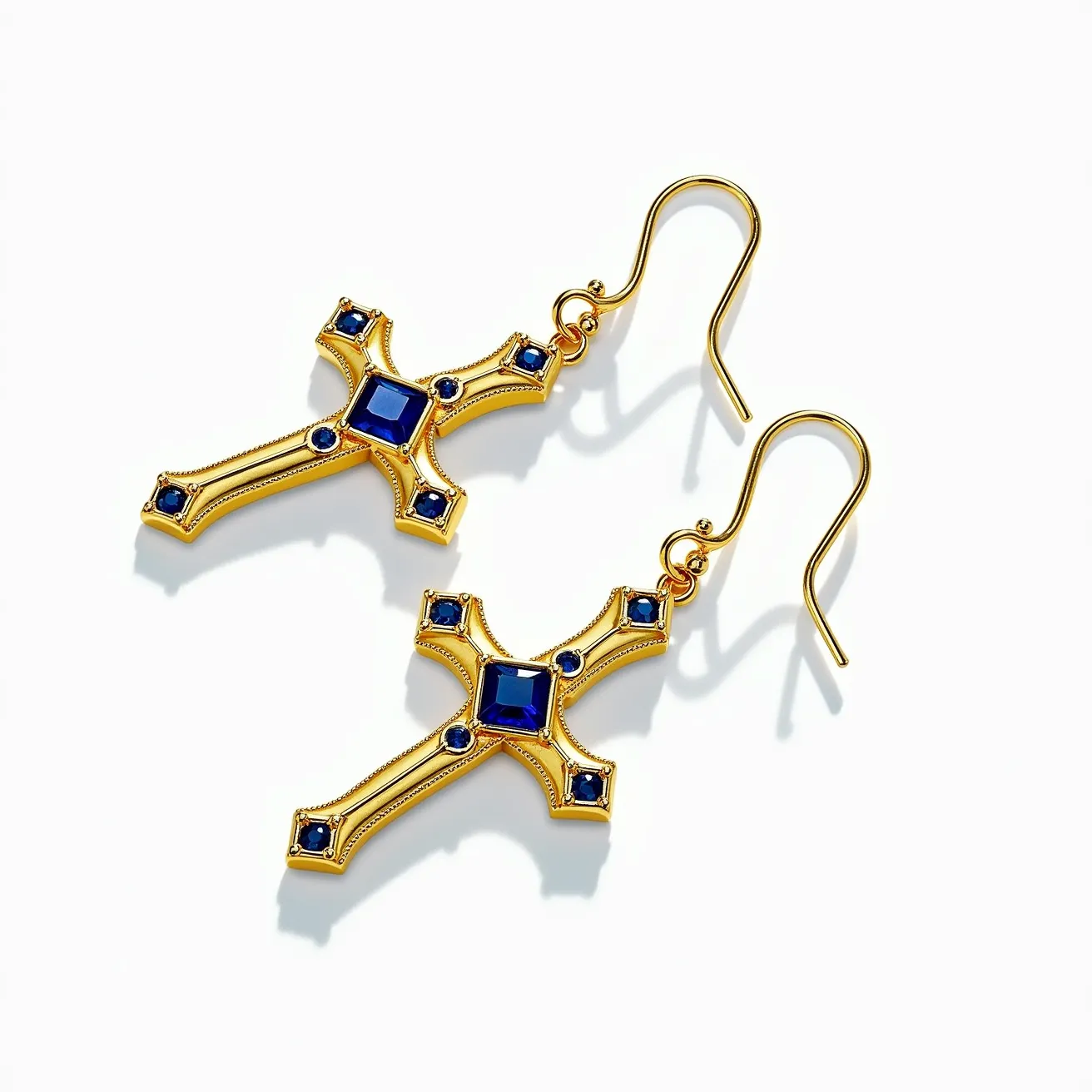 These gold cross earrings feature a polished gold finish, beautifully adorned with vibrant blue gemstones. The gems appear to be square-cut at the center and round-cut at the ends, all set in a flush setting that enhances their elegant appearance. The earrings attach via a classic French hook, providing a secure and stylish clasp that complements the ornate design of the crosses. The rich combination of gold and blue stones gives these earrings a timeless and sophisticated appeal.