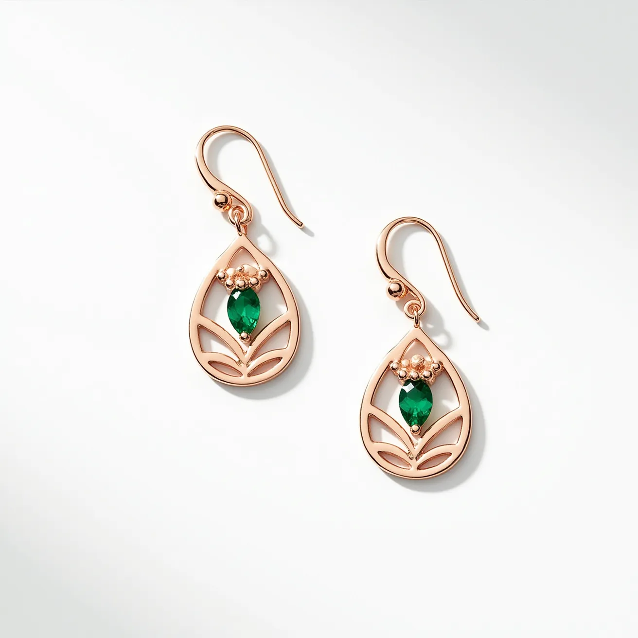 These gold dangle earrings feature an open teardrop design crafted from gold with a polished finish. At the center of each earring is a striking marquise-cut green gemstone, securely set in a bezel setting. Surrounding each stone is a delicate arrangement of small gold bead accents, enhancing the overall elegance and sophistication of the piece. The earrings attach with a simple and elegant fishhook clasp, allowing for ease of wear and a graceful dangle effect. The combination of the gold setting and vibrant green stones creates a timeless and versatile accessory.