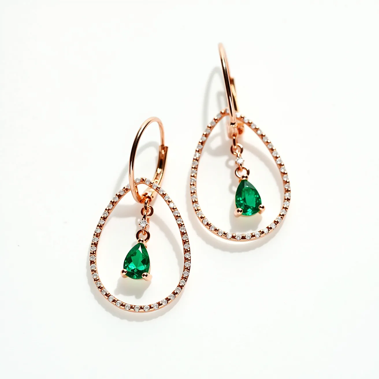 These gold dangle earrings feature a teardrop design with a delicate hoop crafted from gold. Each hoop is elegantly adorned with small, shimmering diamonds set in a pave style, enhancing its luxurious appearance. Suspended within each hoop is a vibrant green teardrop-shaped gemstone, likely an emerald, held securely in a prong setting that allows light to accentuate its color and brilliance. The earrings are attached with a classic lever-back clasp, ensuring both security and ease of wear.