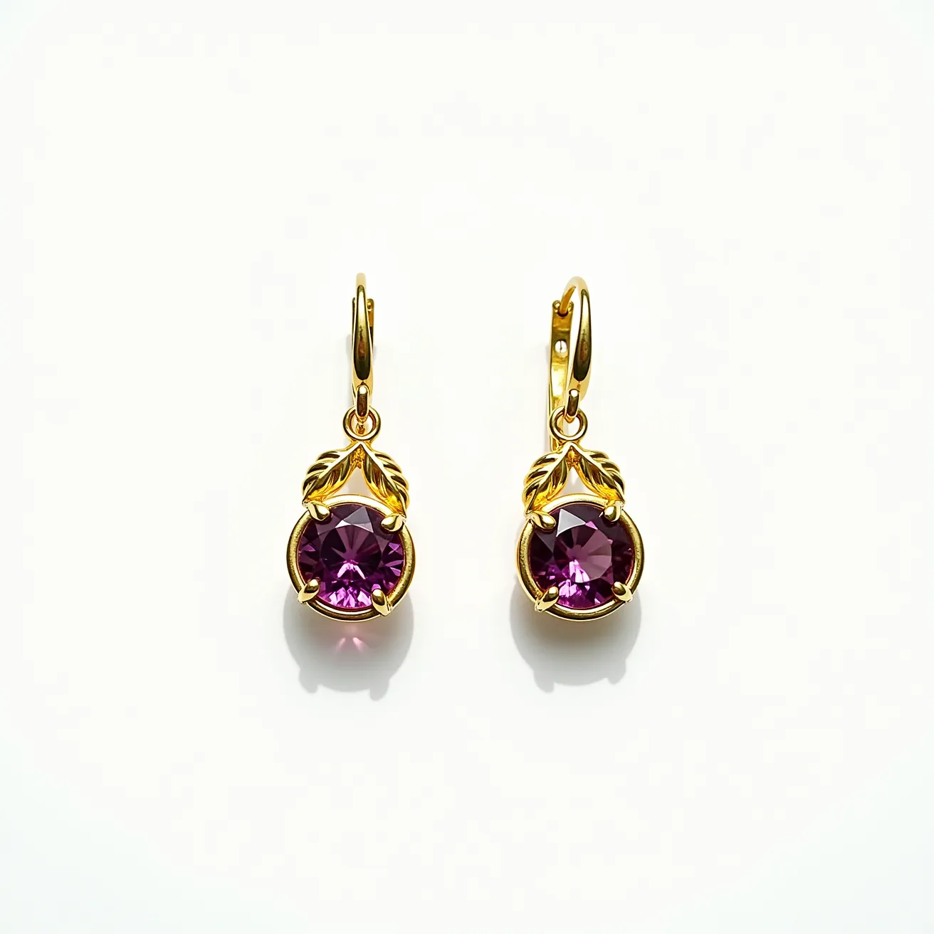 These gold drop earrings feature a sophisticated design with a rich, purple gemstone as the central focus. The stones are round-cut and elegantly set in a bezel setting that highlights their deep color and sparkle. Above the gemstone, delicate gold leaf motifs add an intricate and elegant touch, enhancing the overall design. The earrings are attached with secure lever-back clasps that ensure a comfortable fit while maintaining a stylish appearance.