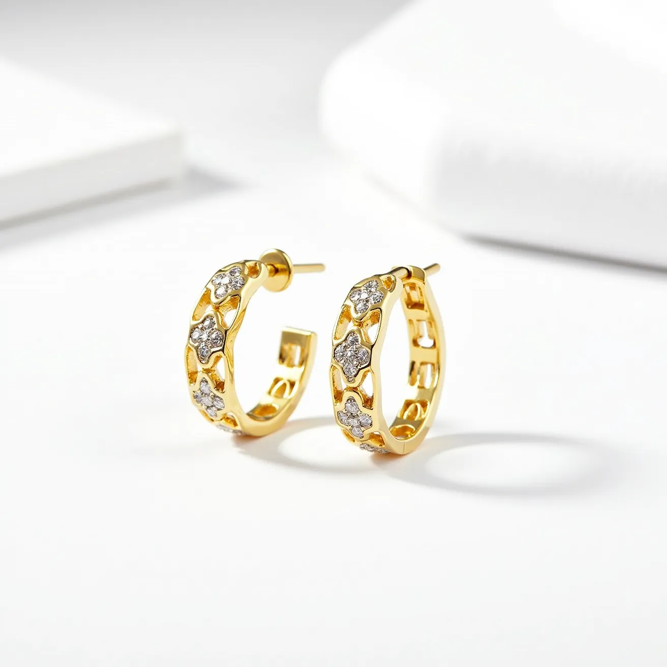 These gold earrings are designed as hoop earrings with a polished yellow gold finish. They feature multiple floral-shaped designs embellished with small, sparkling gems, likely diamonds. The gems are set within each floral shape, suggesting a prong or bezel setting that securely holds them in place. The earrings are equipped with a standard post and butterfly clasp, ensuring a secure fit when worn. These elements combine to create a luxurious and elegant accessory.