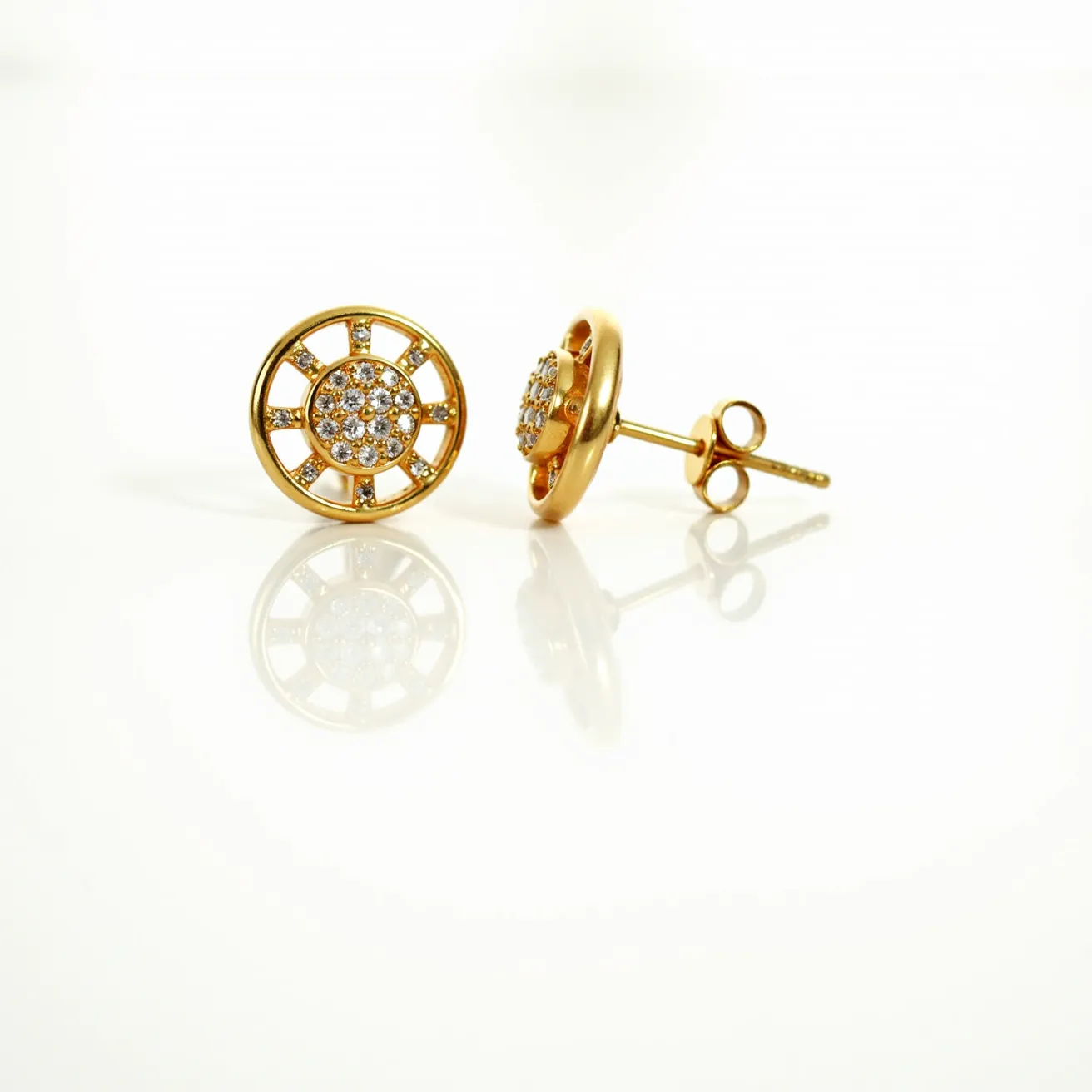 These gold earrings feature a circular design composed of yellow gold with a central cluster of small, round-cut white gemstones, likely diamonds. The cluster is set in a pave setting, providing a sparkling, textured appearance. The surrounding gold structure is open with radiating gold bars extending from the center, further emphasizing the gemstones. These earrings are equipped with a traditional post and butterfly clasp, ensuring a secure fit when worn.