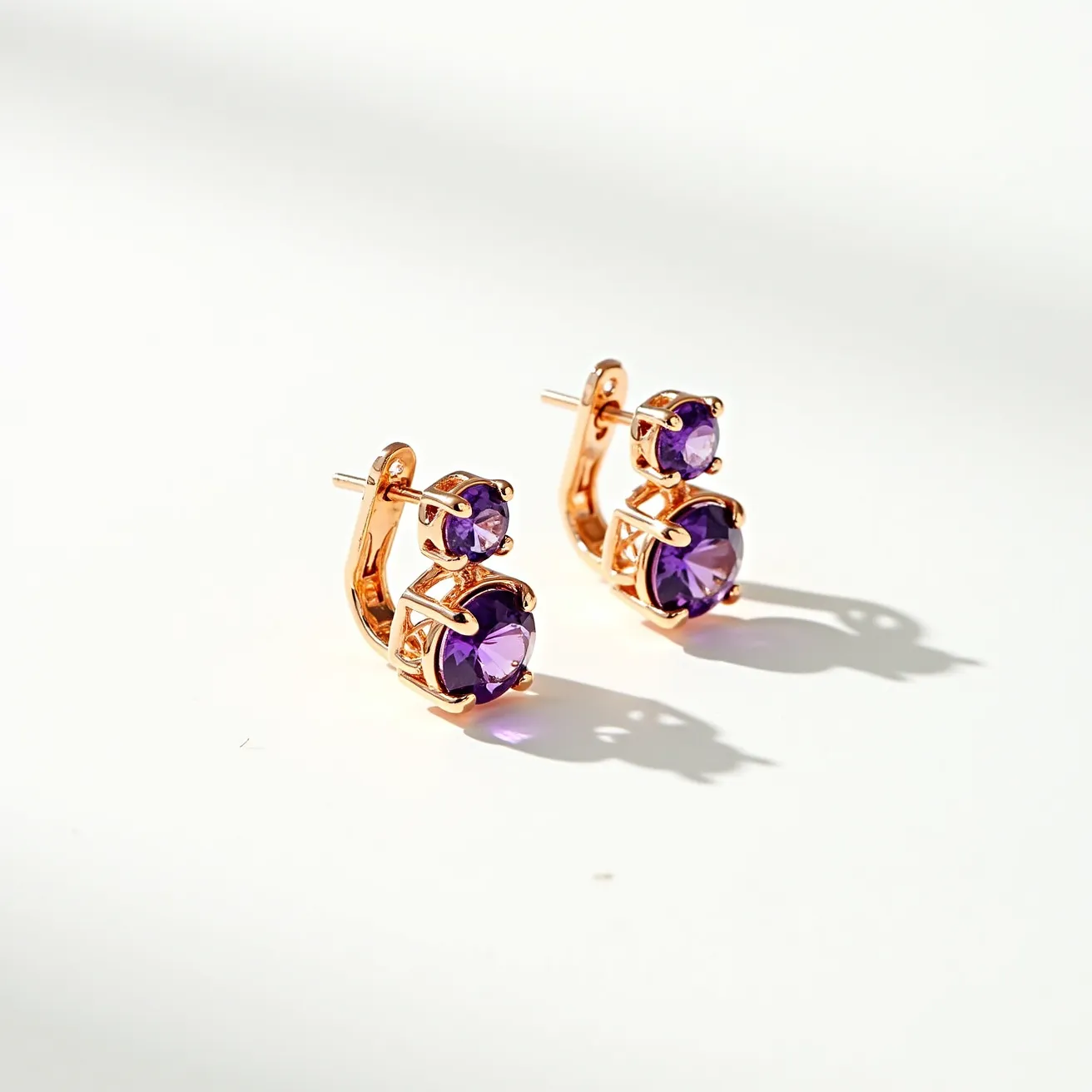 These gold earrings feature a sophisticated design, showcasing two purple gemstones on each piece. The stones appear to be round cut, with a brilliant sparkle that suggests they're possibly amethyst or a similar gem. Each stone is securely held in a classic prong setting, allowing light to enhance their color and brilliance. The earrings are crafted from a polished gold material, adding a warm, elegant touch. They are designed with a post and butterfly clasp, ensuring a secure fit while worn.