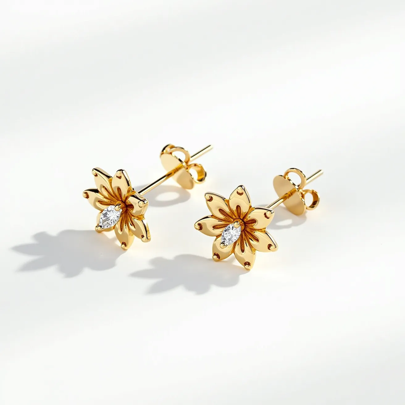 These gold flower earrings feature a beautifully crafted floral design. The petals are made of polished gold, giving them an elegant shine. At the center of each earring is a marquise-cut gem, likely a diamond, set in a secure prong setting that adds a touch of brilliance to the piece. The earrings are equipped with a post and butterfly clasp, ensuring they sit perfectly when worn. The overall design combines simplicity and luxury, making them an exquisite accessory.