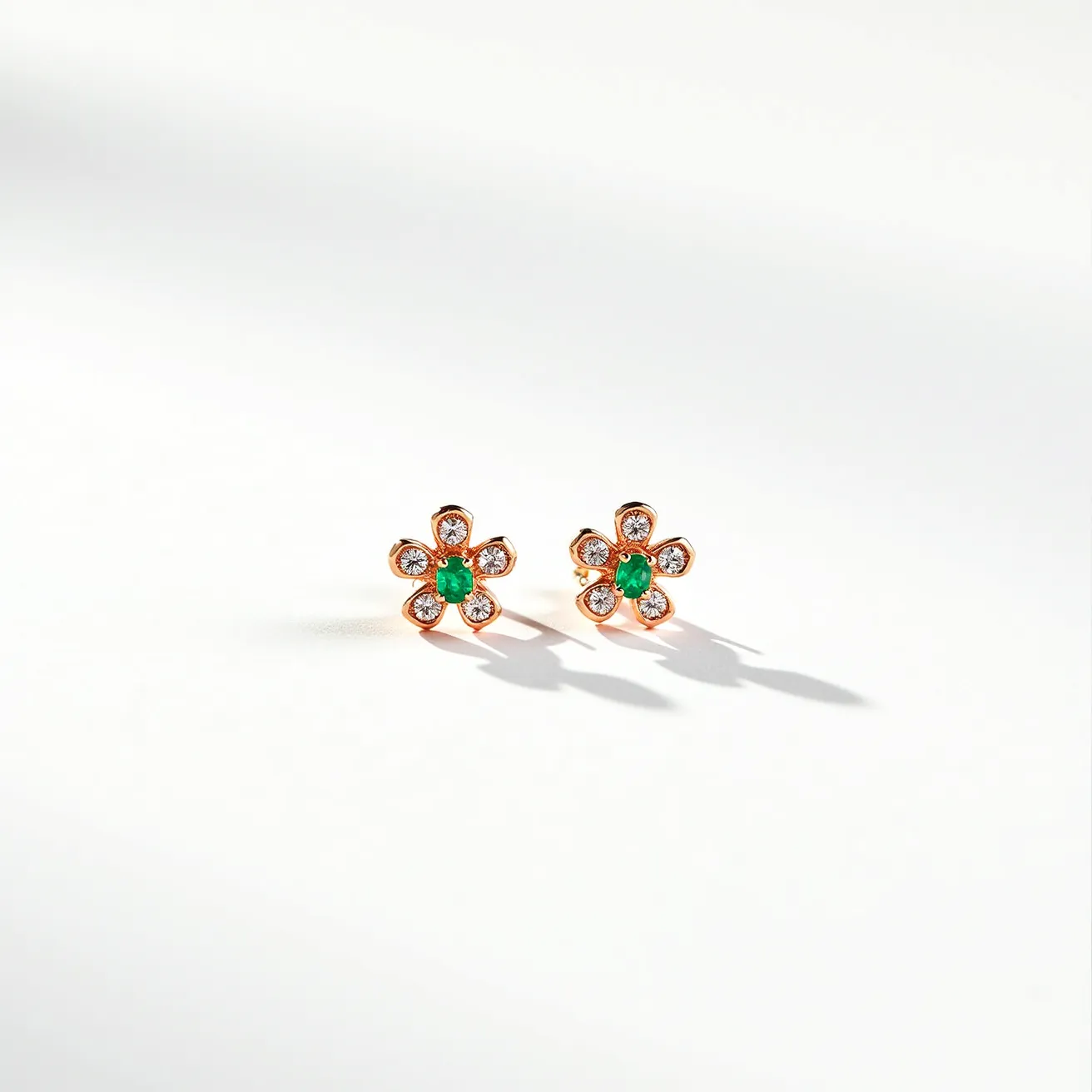 These gold flower earrings feature an elegant floral design crafted from gold. Each petal of the flower is set with a small, round-cut diamond, giving a sparkling contrast to the smooth gold. At the center of each earring lies a striking round-cut emerald, adding a vibrant touch with its rich green hue. The diamonds are neatly set in a prong setting, providing a secure hold while showcasing their brilliance. The earrings are designed with a simple post and butterfly clasp at the back, ensuring a comfortable and secure fit for the wearer.