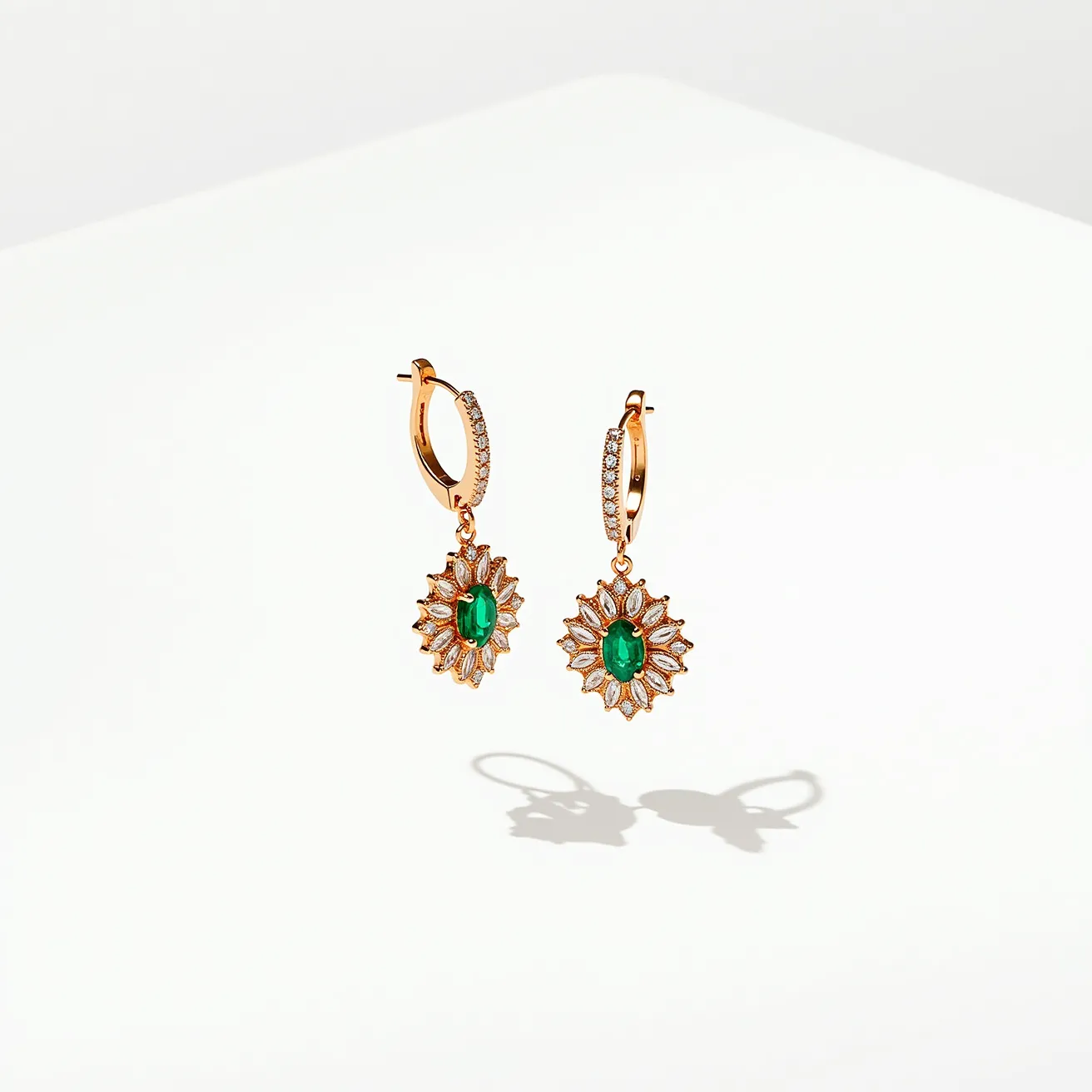 These gold flower earrings feature a striking design with green oval-cut gemstones as the centerpiece, surrounded by petal-like arrays of smaller stones set in a sunburst pattern. The gold provides a warm, elegant backdrop that complements the vivid green. The earrings have a hoop clasp adorned with additional small, clear round stones, enhancing the overall sparkle and charm. The attachment style ensures secure and comfortable wear, making them a glamorous accessory for any occasion.