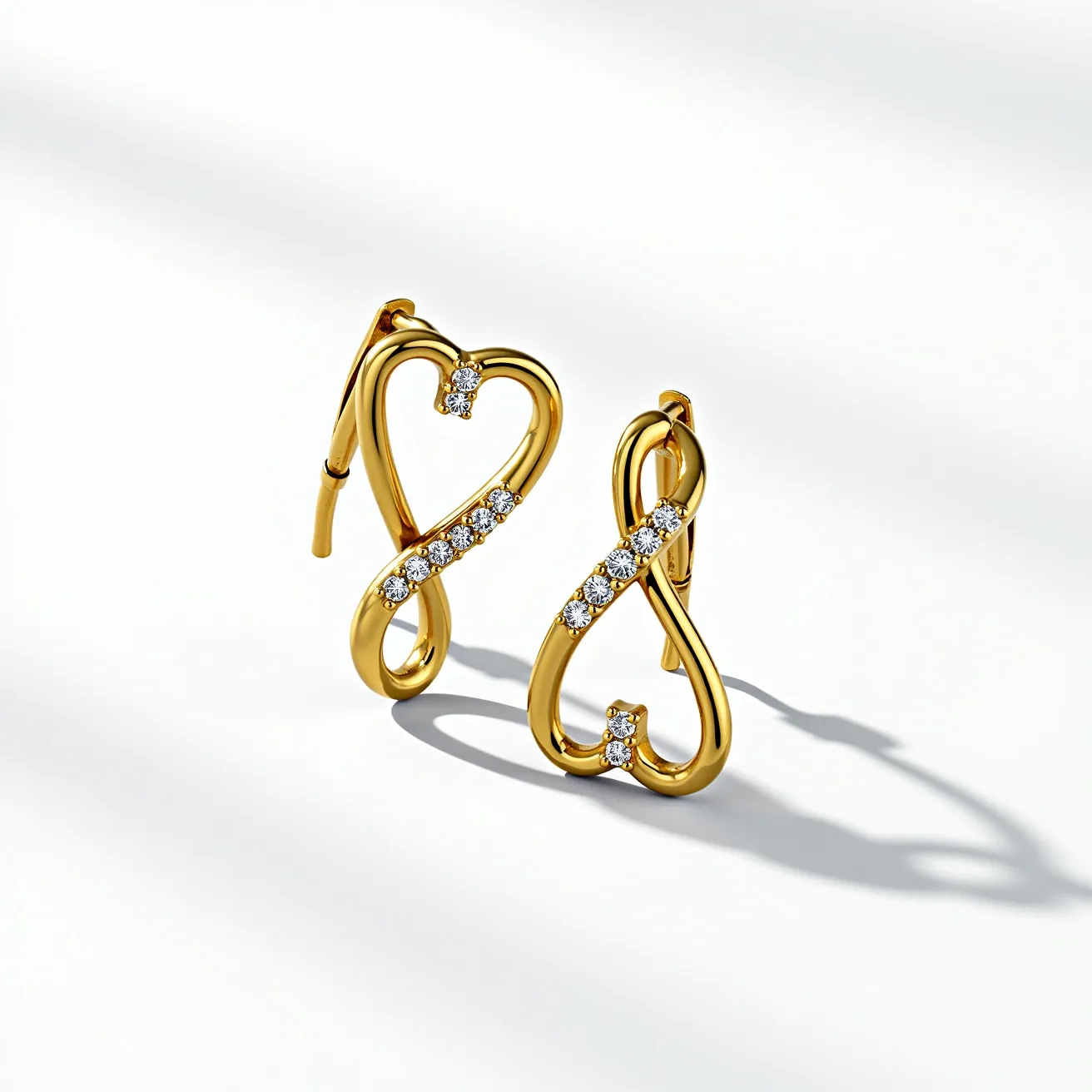 These gold heart earrings feature a sleek, twisted heart-shaped design crafted from polished gold. Each earring is adorned with a series of round, brilliant-cut gemstones, likely diamonds, set along the curvature of the heart. The stones are arranged in a pave setting, allowing them to sparkle prominently against the gold. The earrings are secured with lever-back clasps, ensuring a comfortable and secure fit.