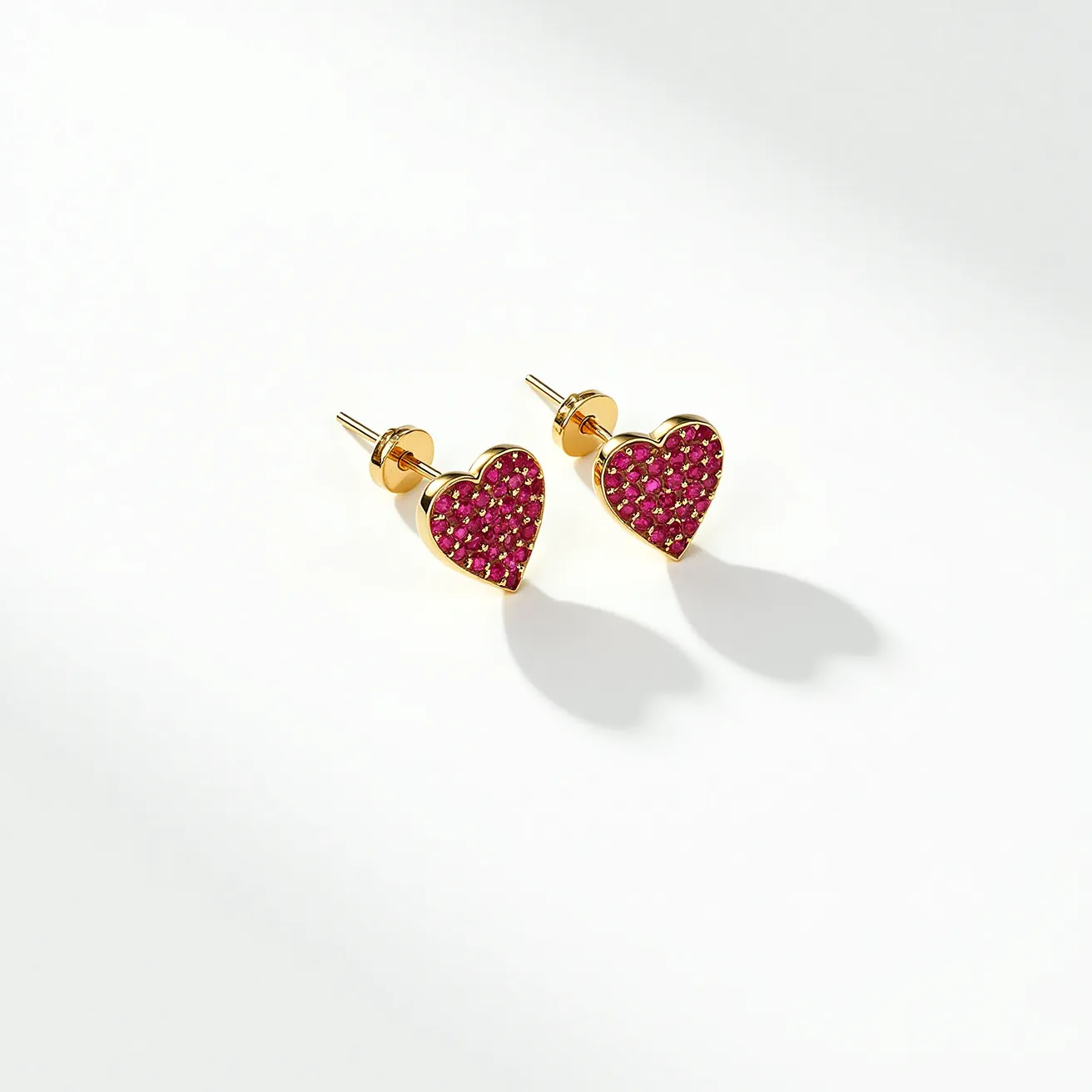 These gold heart earrings feature a vibrant collection of pink stones set into a heart-shaped gold setting. The stones appear to be densely packed, contributing to a rich colorful surface, and are likely small round cuts based on their uniform appearance. The gold frames the stones elegantly, enhancing their brilliance. The earrings have a post and butterfly back for attachment, ensuring a secure fit when worn. The overall design is stylish and sophisticated, combining classic heart motifs with a pop of color from the stones.