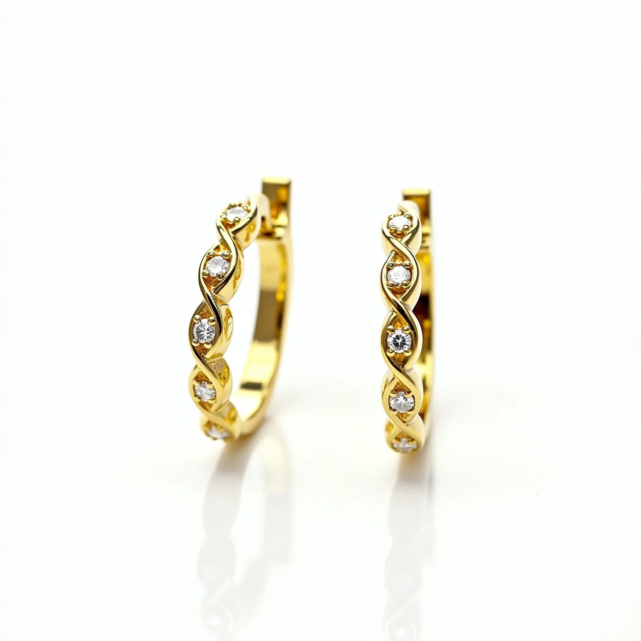 These gold hoop earrings feature a polished gold finish with an elegant intertwining design that houses small, round-cut gemstones. The stones are set in a prong setting, ensuring they are securely held while adding subtle sparkle to the overall design. The earrings utilize a hinged clasp mechanism, which provides both security and ease of use when worn.