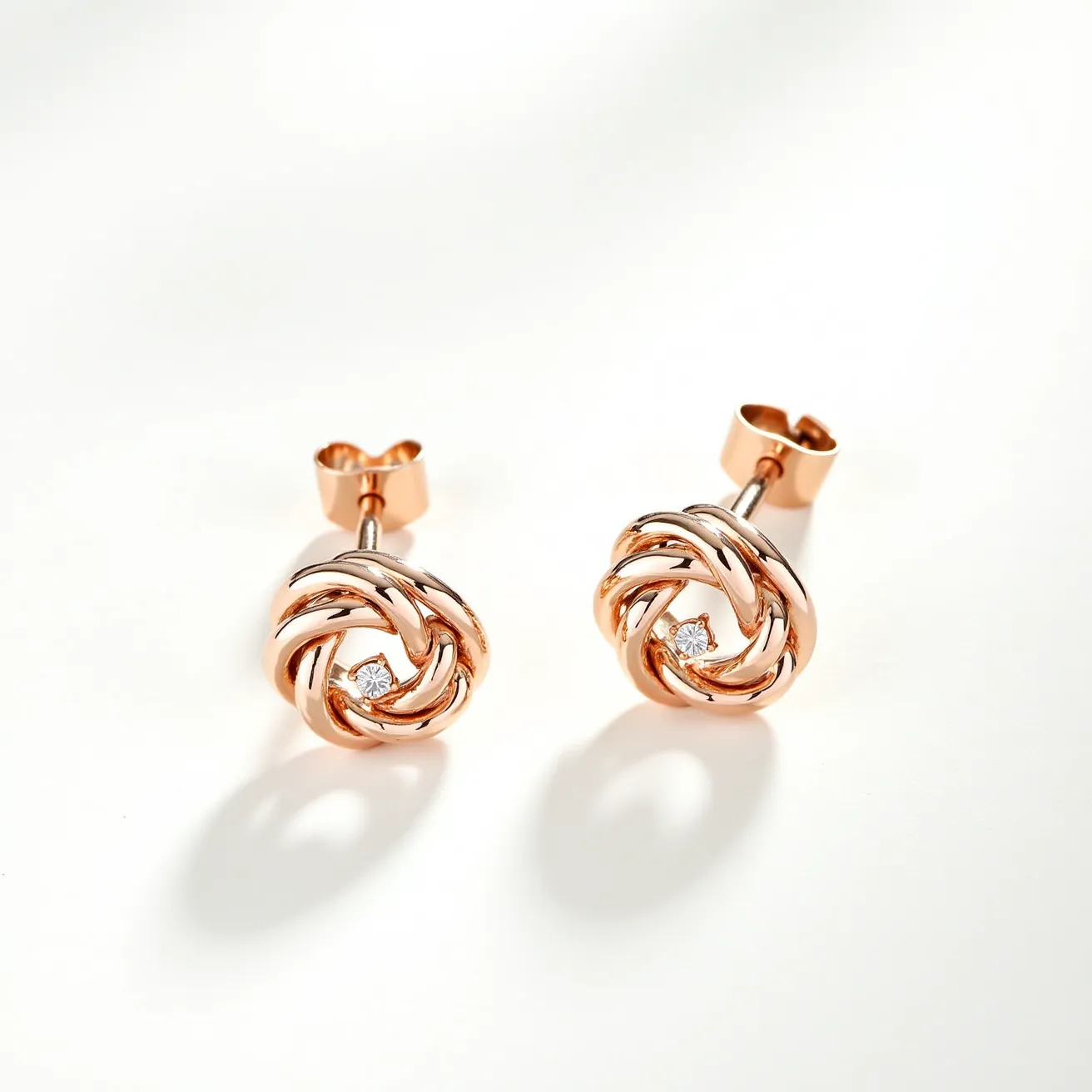 These gold knot earrings feature a sophisticated intertwining design crafted from a polished gold material, exuding a classic and elegant charm. At the center of each earring, a round-cut diamond is securely nestled, adding a touch of sparkle that enhances the overall allure. The diamonds are set in a bezel-like arrangement, ensuring stability while showcasing their brilliance. These earrings are equipped with a traditional push-back clasp, providing a secure and comfortable fit for the wearer.