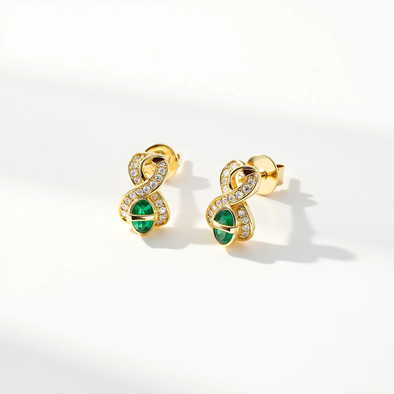 These gold knot earrings showcase an elegant intertwining design, crafted from a polished yellow gold material that enhances their luxurious appearance. The earrings are accentuated by a series of small, round-cut white stones set evenly along the knot, adding a touch of sparkle. Prominently featured at the center of the design is an oval-shaped green gemstone, securely held in place by a classic bezel setting. The earrings are designed with a practical post-back clasp, ensuring a secure and comfortable fit for the wearer.