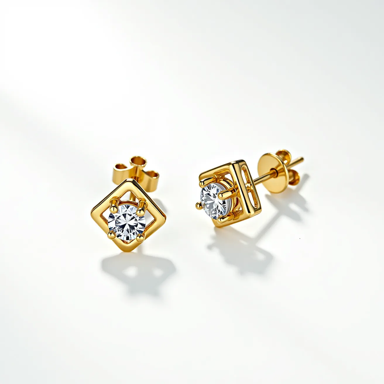 These gold stud earrings feature a classic design with a central round-cut gemstone that appears to be a diamond or a similar sparkling crystal. The stones are securely held in a four-prong setting, which showcases their brilliance and adds a touch of elegance. The gold used in the earrings provides a warm and luxurious appearance, complementing the bright stones. The earrings employ a push-back clasp, making them easy to wear and ensuring a snug fit. The design is enhanced by a unique, open square frame around the stone, offering a modern twist to the traditional stud earring style.