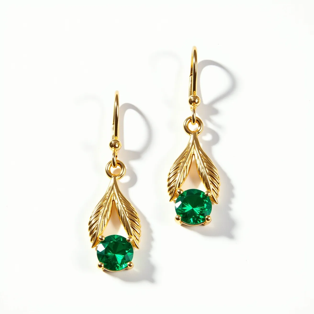 These gold teardrop earrings feature elegant leaf-like designs crafted from gold, adorned with vibrant green gemstones at their centers. The gemstones are round-cut and are securely set in a prong setting, adding a touch of sophistication and brilliance to the design. The earrings have fishhook clasps, providing a simple and stylish attachment method, enhancing their ease of wear while maintaining their elegant appearance. The combination of the gold and green stones creates a harmonious and luxurious look, perfect for enhancing any outfit.