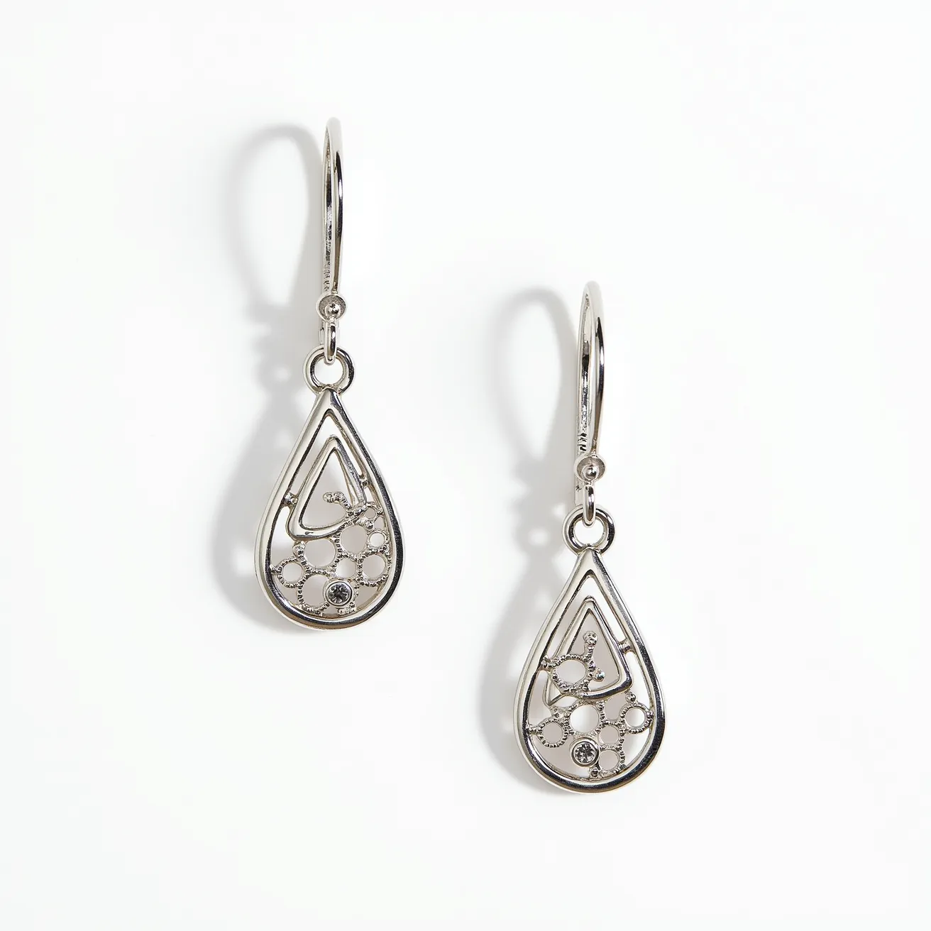 These gold teardrop earrings feature a delicate openwork design, crafted from polished metal that may be gold or gold-toned. The teardrop shape includes an intricate pattern with small circular elements, some of which are adorned with small, clear stones, resembling diamonds, in bezel-like settings. The earrings are suspended from simple, curved hooks that provide a secure and classic attachment, enhancing their elegant and timeless appeal.