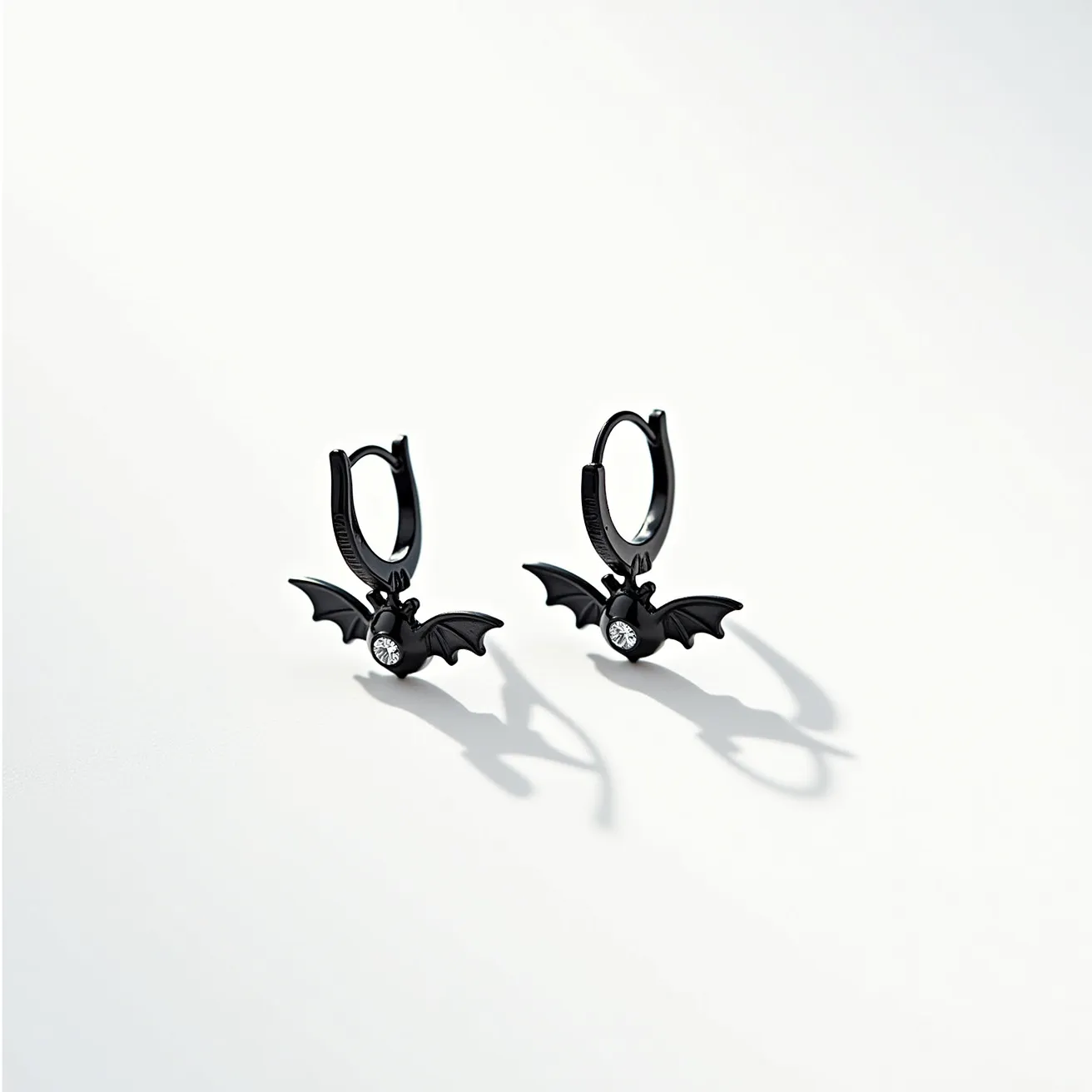 These Halloween earrings feature an intriguing design with bat-shaped charms made from a black metal, likely a form of coated or oxidized sterling silver, adding to their eerie allure. Each bat charm is adorned with a single, sparkling clear gem that appears to be a round-cut white zircon or diamond, set minimally into the body of the bat for an unobtrusive yet eye-catching effect. The earrings utilize a hoop clasp for secure wear, seamlessly blending functionality with the thematic, spooky aesthetic of the piece.