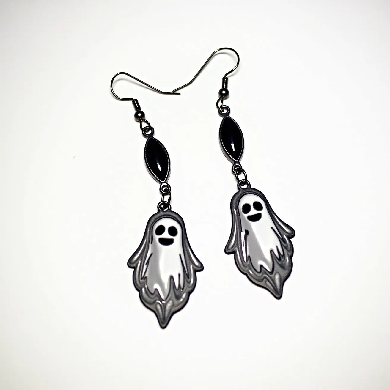 These halloween earrings feature charming ghost designs made from a smooth, likely acrylic material with a black and white color scheme. The ghosts dangle from a metallic connection, each topped with an oval-shaped, black stone or enamel decoration. The stones have a smooth, glossy finish that provides a nice contrast to the ghostly motifs. The earrings are attached to ear hooks, which are most likely made from a metal like stainless steel, ensuring both durability and ease of use. The combination of whimsical ghost shapes and sleek black elements makes these earrings an ideal accessory for Halloween festivities.