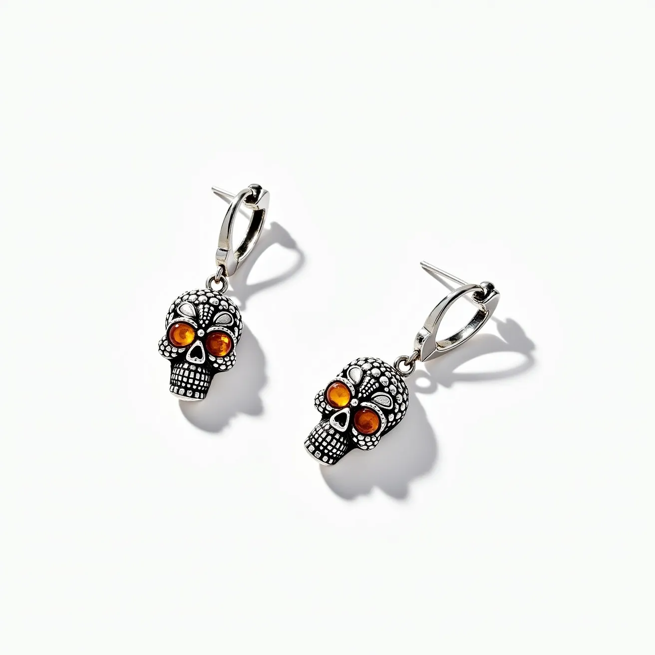 These halloween earrings feature intricately designed skull motifs crafted from a silver-toned metal. The skulls are adorned with orange gemstone eyes that appear to be round cut and bezel set, adding a vibrant touch to the design. The earrings are equipped with a lever back clasp, allowing for secure and comfortable wear. The attention to detail in the skull patterns contributes to the festive and spooky aesthetic, perfect for Halloween celebrations.