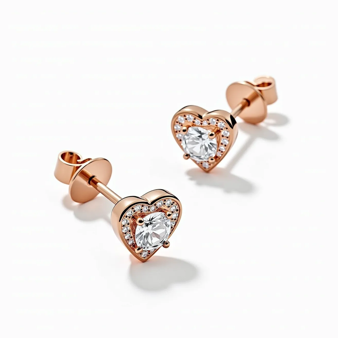 These heart diamond earrings feature a stunning central round-cut diamond set in a heart-shaped design, surrounded by smaller, brilliant-cut diamonds that enhance the sparkle. The metals appear to be rose gold, providing a warm and elegant backdrop for the gemstones. The central diamond is secured with a prong setting, ensuring it remains the focal point, while the halo of smaller diamonds is likely set in a pavé style, adding texture and brilliance. The earrings utilize a post and butterfly clasp attachment, a classic choice for security and comfort.