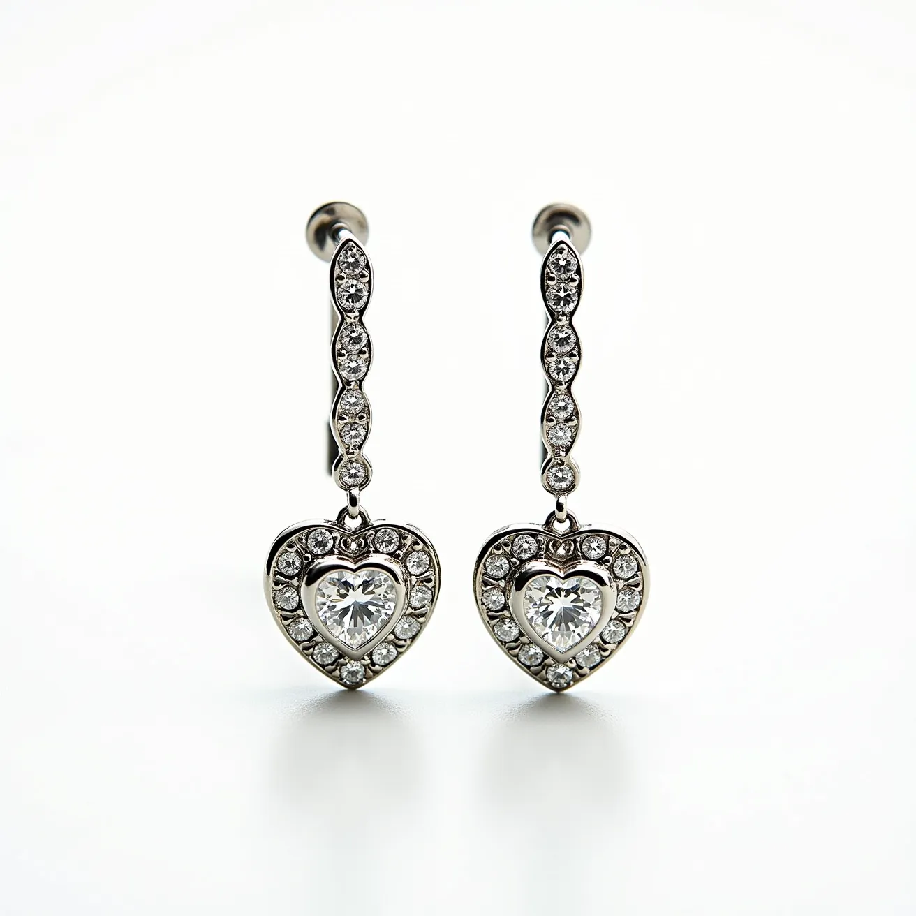 These heart diamond earrings feature a central heart-shaped diamond in each earring, elegantly surrounded by a halo of smaller round diamonds. The heart diamonds are expertly cut to enhance their brilliance and are set securely in a heart-shaped setting. The earrings have a drop design with additional round diamonds adorning the connection to the clasp, adding to the overall sparkle. The metal appears to be a polished white gold or platinum, providing a luxurious backdrop that complements the clarity and shine of the diamonds. The earrings are equipped with a post backing, ensuring a secure and comfortable fit for the wearer.