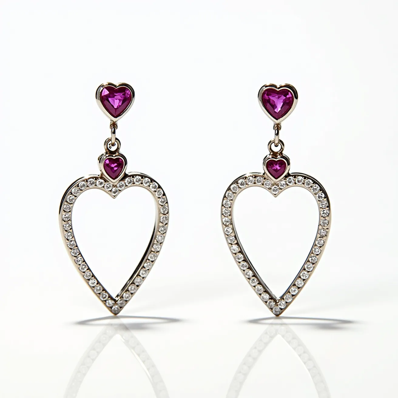 These heart diamond earrings feature an elegant design, with heart-shaped frames encrusted with small round diamonds, set in a pave pattern that enhances their sparkle. Each earring displays a striking purple heart-shaped gemstone as its central focus, both at the top and in the smaller setting below, likely set in a prong setting to secure the gems and enhance their visibility. The meticulous arrangement and choice of materials suggest a luxurious appeal, combining the brilliance of diamonds with the rich hue of the purple gemstones. The earrings connect to the wearer with a post-back or similar attachment style, providing a secure and comfortable fit.