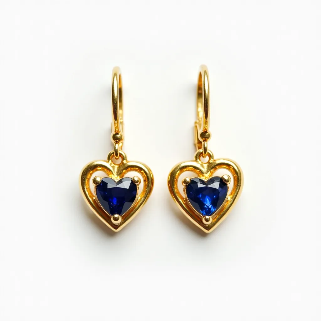 These heart earrings feature a striking design with a central blue gemstone, possibly a sapphire, cut in a heart shape. The stone is securely held within a gold setting that outlines the heart shape, adding a touch of elegance. Each earring attaches via a simple gold hook clasp, enhancing the overall classic and refined appearance. The combination of the blue gemstone with the gold metal creates a visually appealing contrast, making these earrings an elegant accessory.