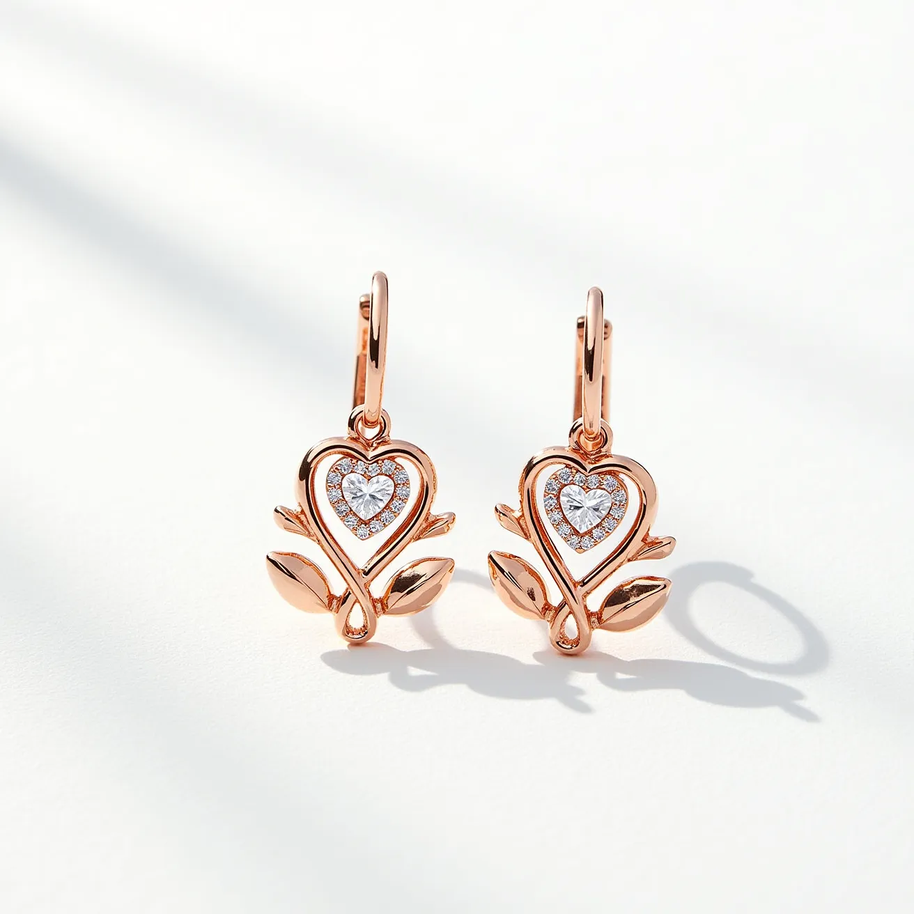 These heart earrings feature a delicate design crafted from rose gold metal, shaped into an intricate heart pattern entwined with leaves. At the center of each heart sits a sparkling heart-shaped clear gemstone, surrounded by smaller stones in a pavé setting, enhancing the overall radiance. The earrings are designed with lever-back clasps, offering a secure and stylish attachment method. The combination of the rose gold and the brilliant stones gives the earrings an elegant and sophisticated appearance, perfect for adding a touch of elegance to any ensemble.