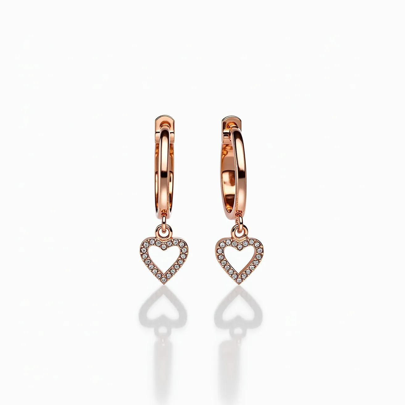 These heart earrings feature a delicate design in polished rose gold. The hearts are outlined with small, round-cut gems, likely diamonds, set closely to give a continuous shimmering effect. Each heart dangles from a smooth, circular hoop, which serves as both the attachment and clasp mechanism. The design’s elegance is highlighted by the seamless integration of the stones into the rose gold setting, making them versatile for various occasions.