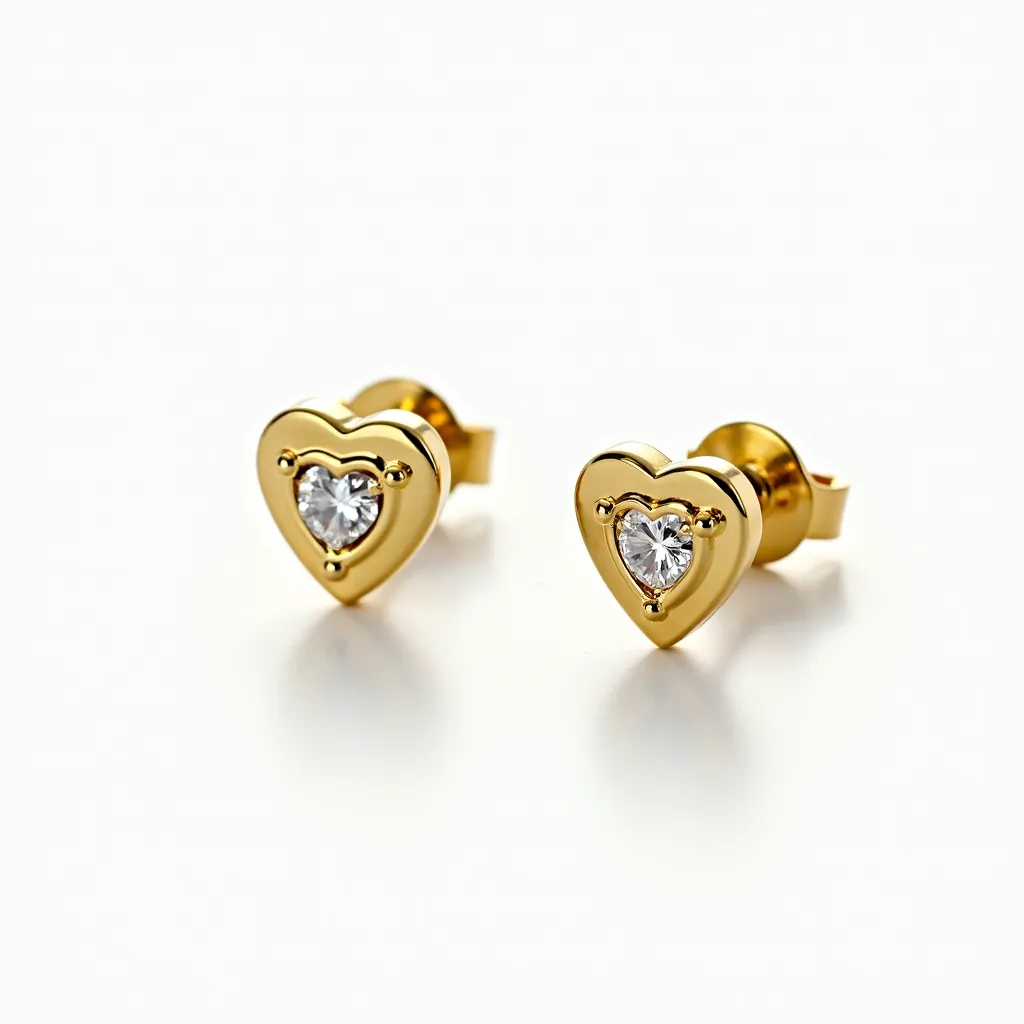 These heart stud earrings feature a striking design crafted from polished gold metal, forming the outline of a heart shape. Centrally set within each heart is a brilliant-cut gemstone, possibly a diamond or diamond-like stone, held securely in place by a bezel setting that enhances its brilliance. The earrings are equipped with a classic post and butterfly clasp attachment, ensuring they stay comfortably and securely in place when worn. The combination of the gold finish and sparkling stones creates a timeless and elegant appearance.