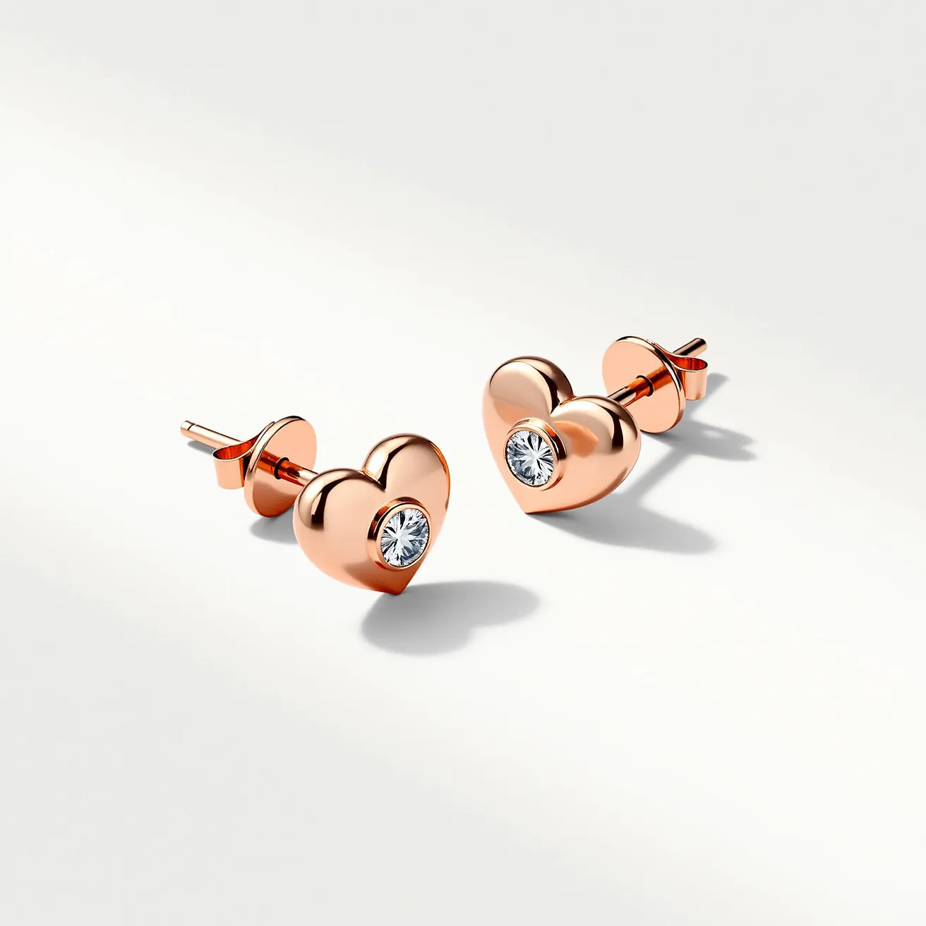 These heart stud earrings are crafted from rose gold, giving them a warm and elegant hue. At the center of each earring is a single round-cut gemstone, likely a diamond, which is set securely in a bezel setting. The attachment features a classic post and clutch back, ensuring both comfort and security when worn. The overall design is simple yet sophisticated, with the heart shape subtly highlighting the central gem's sparkle.