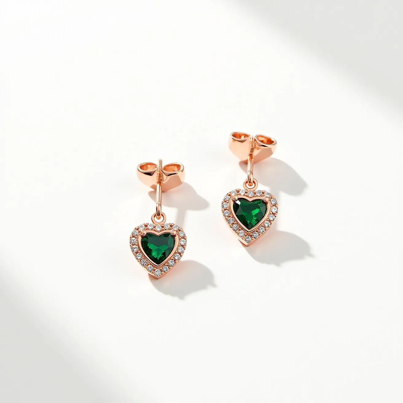 These heart stud earrings feature a captivating design with a central heart-shaped green gemstone, which is beautifully faceted to enhance its luster. Surrounding the central stone, a halo of smaller, clear stones are set in a pavé style, adding sparkle and contrast to the design. The earrings are crafted in a warm-toned metal, possibly rose gold or gold-plated, which complements the green and clear stones elegantly. Each earring is attached with a simple post-and-butterfly back, ensuring secure and comfortable wear. The overall design is both elegant and playful, making it a versatile addition to various styles.