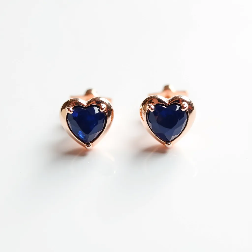 These heart stud earrings feature a polished rose gold setting, elegantly encasing deep blue heart-shaped gemstones. The gemstones are faceted, enhancing their luster and depth of color. Each stone is securely held in place by three prongs, ensuring stability and elegance. The earrings have a classic stud post and butterfly clutch attachment for secure and comfortable wearing. The combination of the rose gold and the vibrant blue stones creates a striking and harmonious contrast, making these earrings an attractive piece.