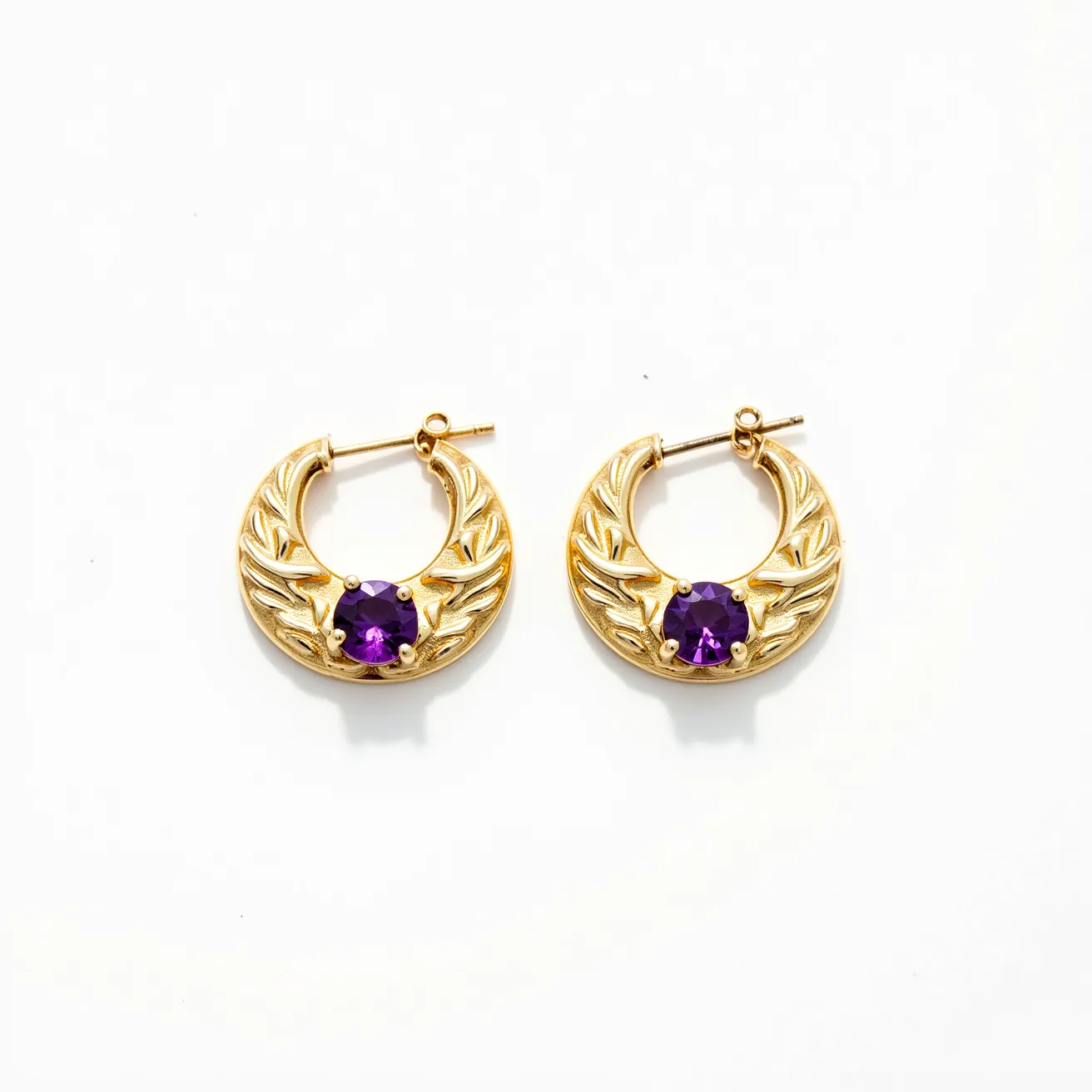 These hoop earrings feature a gold-toned metal with an intricate, embossed design that mimics the appearance of delicate laurel leaves. At the center of each hoop is a prominent round-cut purple gemstone, securely set in a four-prong setting, adding a touch of elegance and color contrast to the overall design. The earrings are equipped with a post and latch back clasp, ensuring a secure fit when worn. The combination of metal and gemstone gives the earrings a classic yet vibrant appeal, suitable for various occasions.