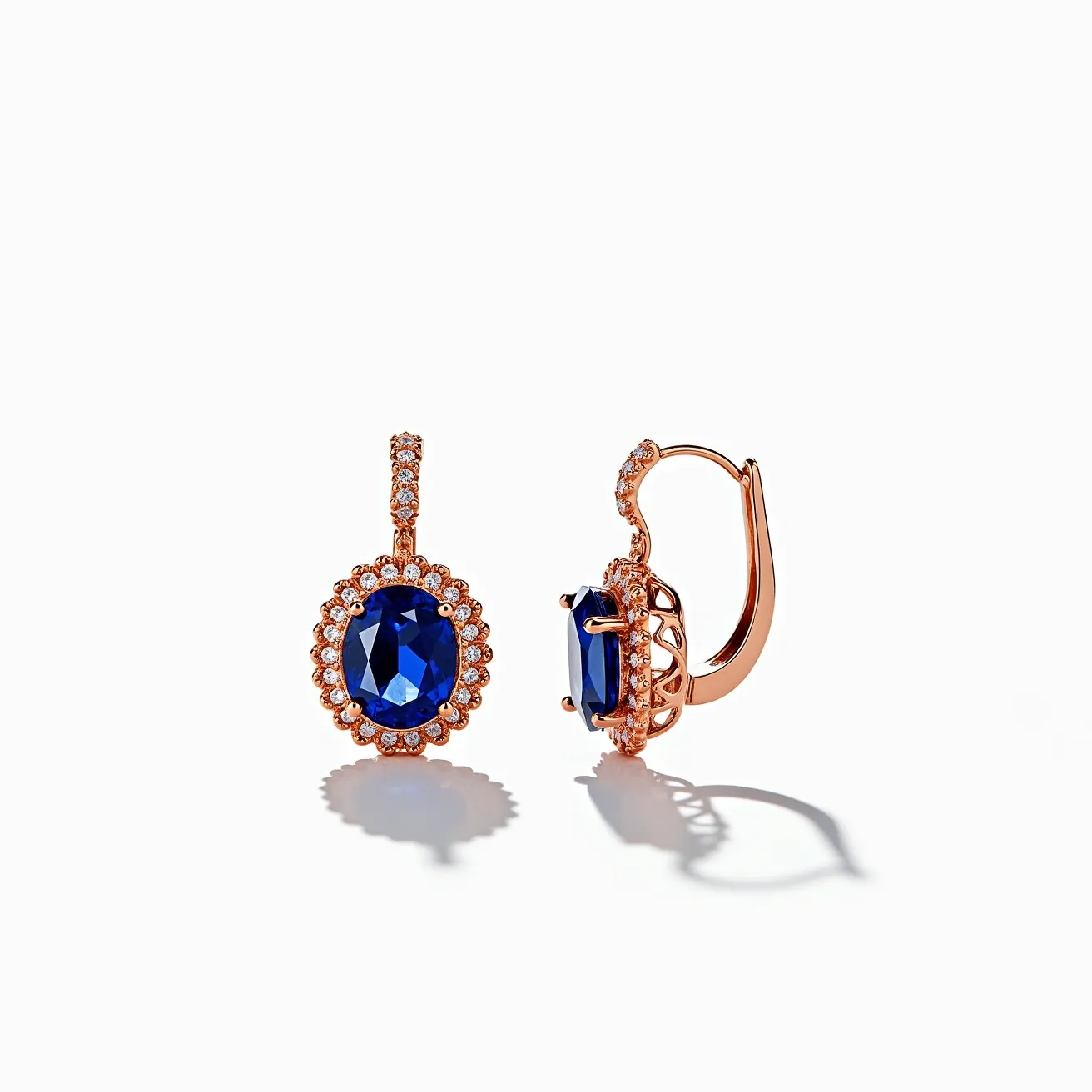 These leverback earrings feature a stunning design with a prominent oval-shaped blue gemstone, likely sapphire, as the centerpiece. The gemstone is faceted to enhance its brilliance and is set within a halo of smaller round diamonds, adding to the overall sparkle and elegance. These diamonds appear to be in a pavé setting, closely encircling the center stone. The earrings are crafted in a rose gold material, which beautifully complements the rich blue of the central stones. The leverback clasp ensures a secure fastening, providing both style and comfort for the wearer.