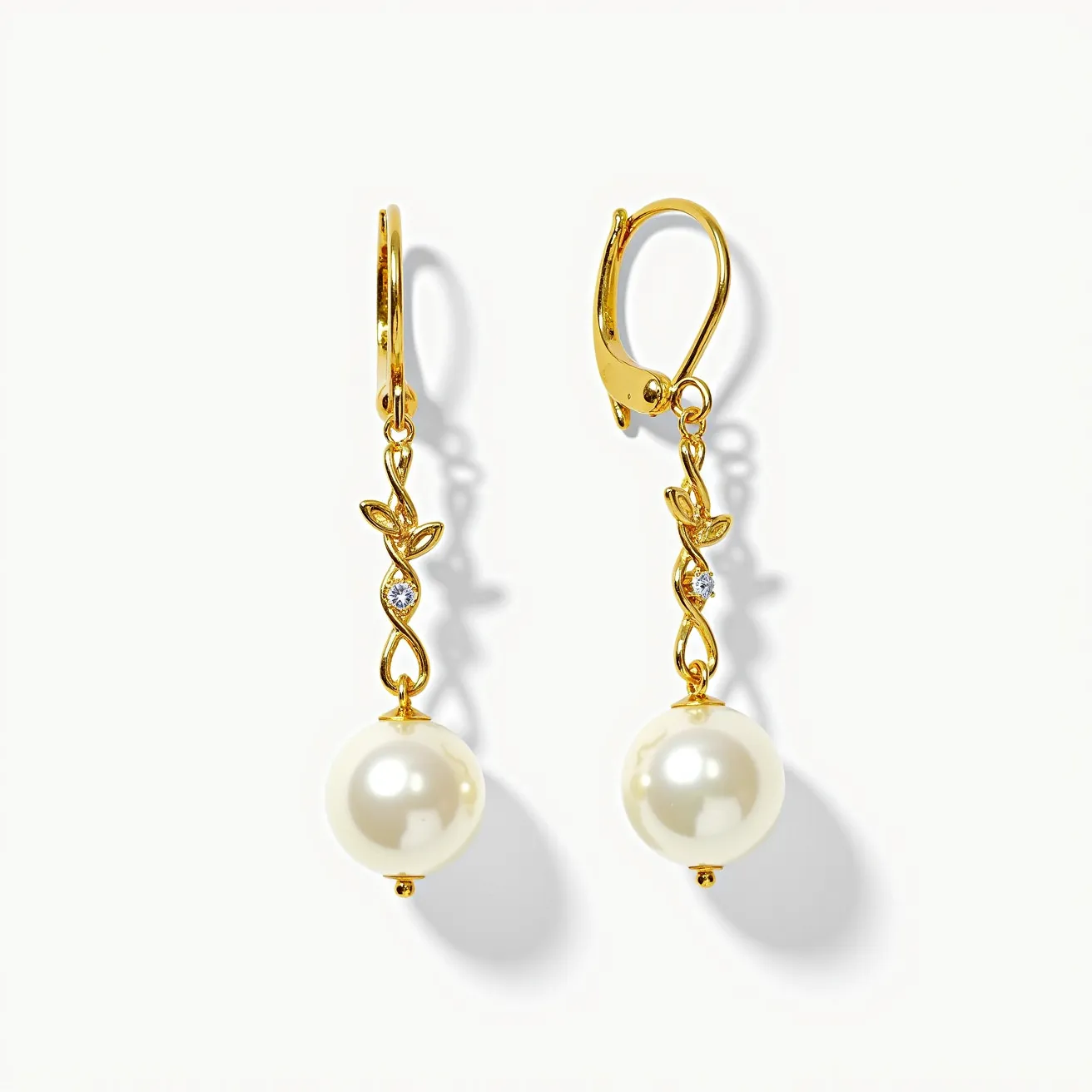 These leverback earrings feature a gold-toned metal structure designed in an elegant vine motif. The earrings are adorned with two gemstones set in the curves of the vine, likely diamonds or diamond simulants, adding a touch of sparkle. At the end of the vine, a large, lustrous pearl hangs, serving as the focal point of the piece. The pearl is round and perfectly smooth, lending a classic elegance to the design. The leverback clasp provides a secure attachment that ensures comfortable and reliable wear.