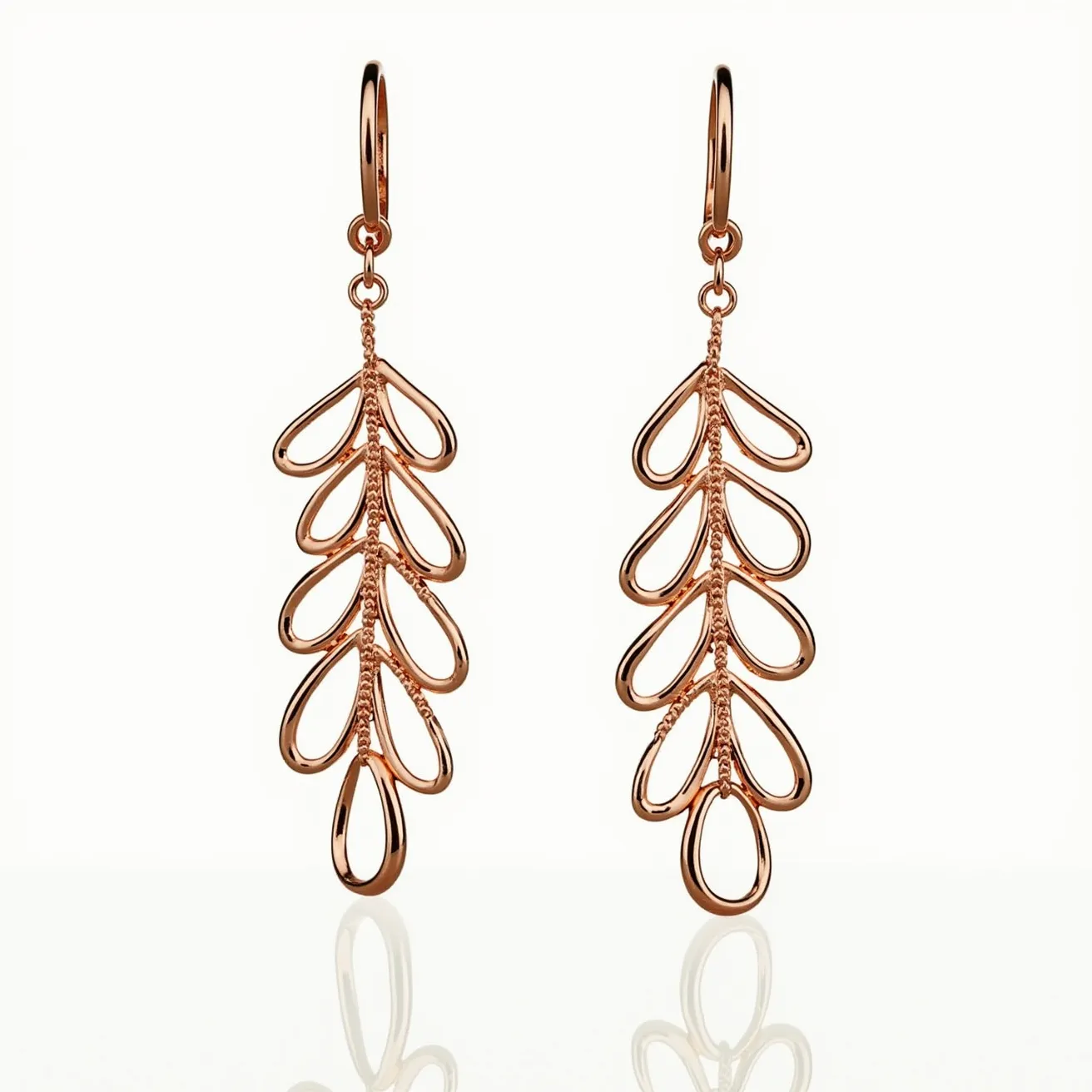 These long earrings feature an elegant design crafted from rose gold, exhibiting a series of teardrop-shaped elements arranged akin to the leaves of a vine. The metal is polished, giving the earrings a glossy finish that accentuates the intricate openwork pattern. Each element is connected seamlessly, showcasing a delicate yet bold design. The earrings are completed with a hook attachment at the top, facilitating easy wear and a graceful dangle effect. There are no gemstones or additional embellishments, allowing the metalwork to be the focal point of these sophisticated earrings.