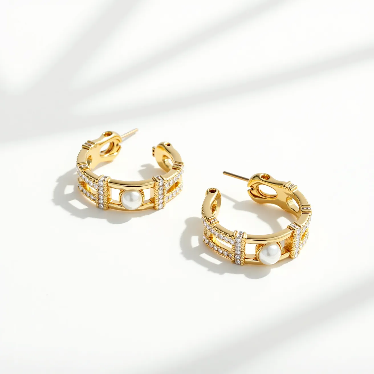 These loop earrings exhibit a luxurious design, crafted primarily from a shiny gold-toned metal. The outer part of the earrings features a series of small, sparkling gemstones, possibly diamonds, arranged in a pave setting along the surface, adding a touch of elegance and brilliance. The central focus of each earring is a single smooth, round pearl that is prominently set, creating a classic and sophisticated aesthetic. The earrings are constructed with a post and latch clasp mechanism, ensuring a secure fit when worn. Overall, these earrings combine classic elements with modern sparkle.