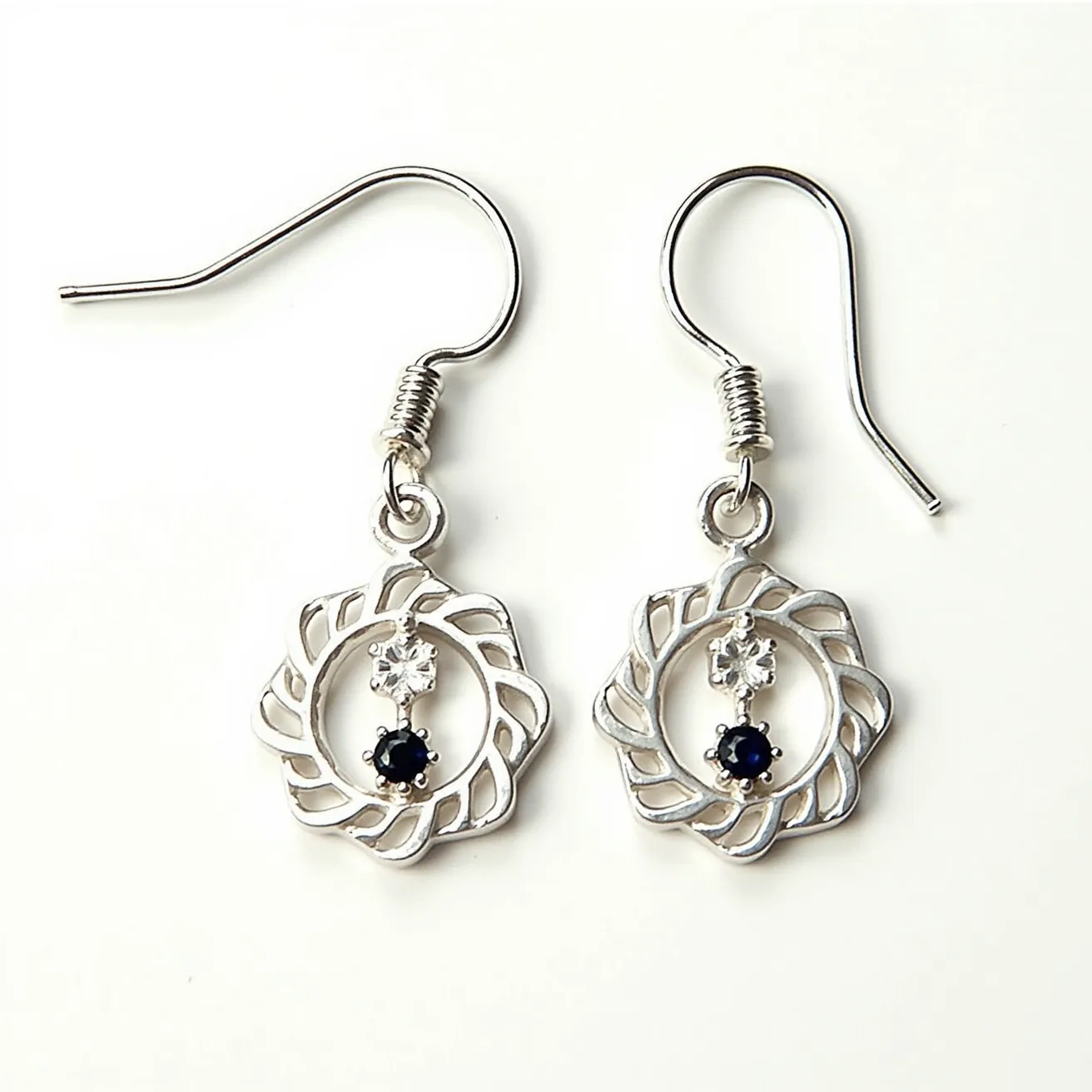 These men's dangle earring features a delicate silver design with an intricate, open-loop pattern resembling a floral motif. At the center, there are two distinct gems: a clear gem with a round cut set in a prong setting, and below it, a darker gem, likely a blue or black stone, also round-cut and set in a similar prong style. The earrings use a fish hook clasp for attachment, providing an elegant and classic look suitable for various occasions.