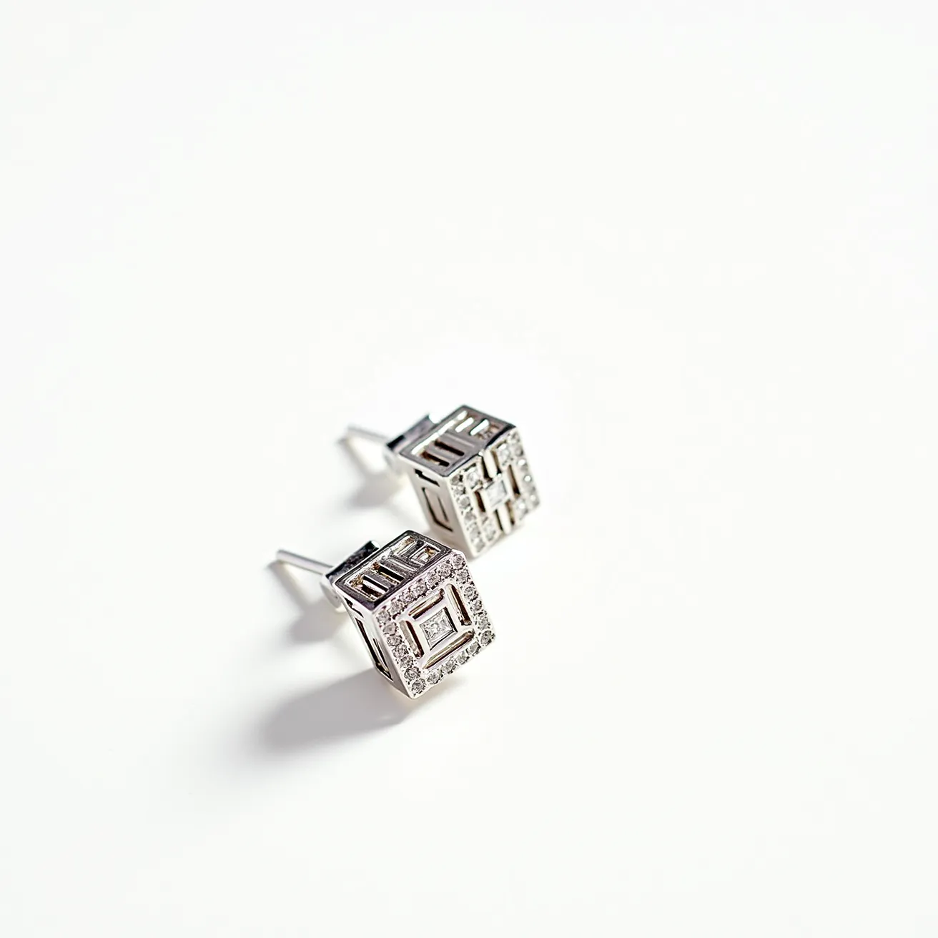 These men's earrings feature a geometric cube design crafted from a lustrous metallic material, likely silver or white gold. The surface is adorned with small, clear gems that are meticulously set in a pave style, adding a subtle sparkle. The cube shape is accentuated by linear cutouts, creating a modern and sophisticated appearance. These earrings are secured with a traditional post and butterfly clutch back, providing a secure fit. The combination of sleek metalwork and precise stone setting makes these earrings a stylish accessory for contemporary fashion.