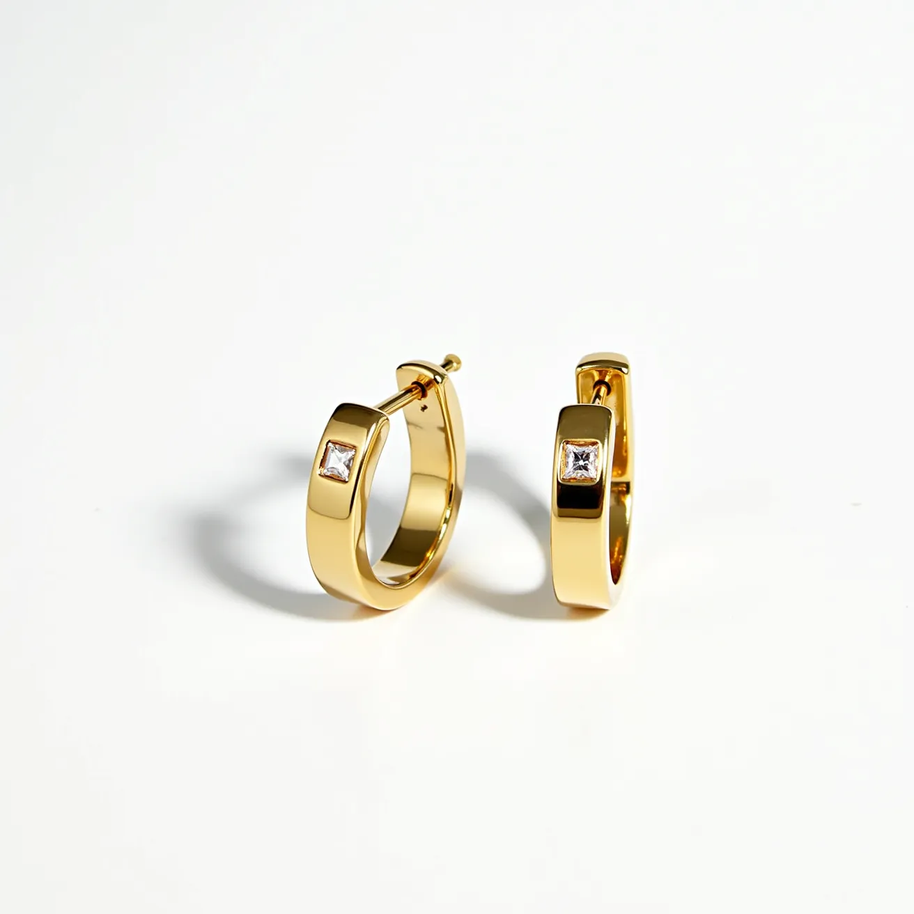 These mens hoop earrings are crafted from a polished gold-toned metal, giving them a sleek and sophisticated appearance. Each earring features a single square-cut gem, which is securely set into the hoop in a bezel setting. The stones are prominently displayed, adding a touch of elegance to the overall design. The hoops are equipped with hinged clasps, providing a secure and easy-to-use attachment method. These earrings combine classic style with modern elements, making them a versatile accessory for various occasions.