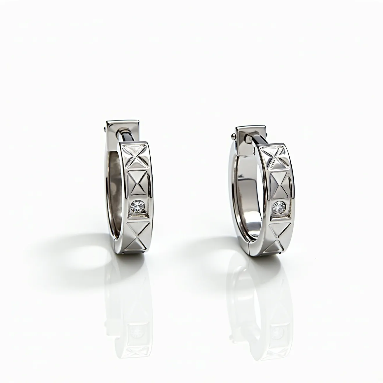 These mens hoop earrings are crafted from a sleek, silver-toned metal, exuding a modern and polished appearance. Each earring features a prominent, round-cut gem, likely a diamond, securely set within the hoop. The setting is subtle, allowing the gem to catch light effectively while maintaining a clean overall design. The surface of the hoops is adorned with distinct geometric X patterns, adding a touch of contemporary flair. These earrings are equipped with a hinged clasp, ensuring ease of use and secure fastening when worn.