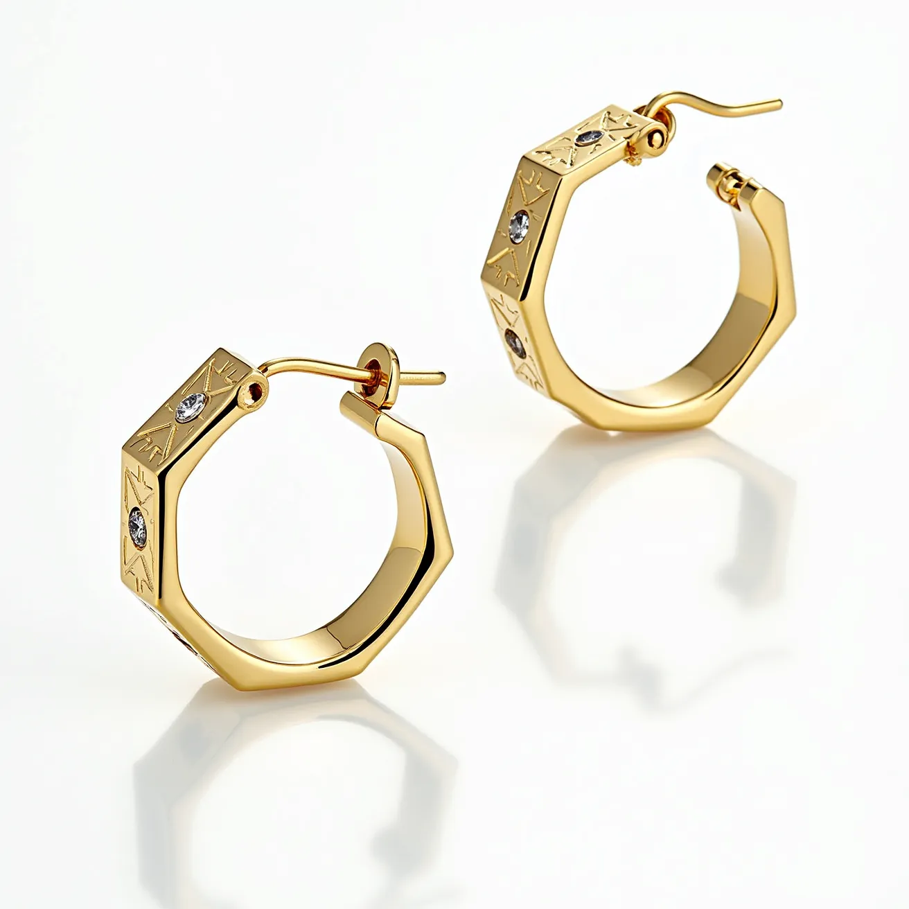 These mens hoop earrings are made of gold-toned metal with a hexagonal design, adding a modern angular twist to the classic hoop shape. Each earring features three small round-cut stones, likely diamonds or cubic zirconia, set in a bezel setting that enhances their sparkling appeal. The surface of the hoops is adorned with subtle engravings that contribute to their stylish and sophisticated appearance. The earrings have a hinged clasp mechanism, ensuring a secure closure and ease of wear.