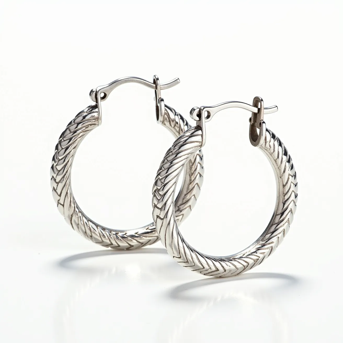 These men's hoop earrings are crafted from a polished silver material, featuring an intricate braided texture that adds a sophisticated and stylish flair. The design showcases a smooth, rounded form that catches light, enhancing the detailed craftsmanship. The hoops are secured with a hinged clasp mechanism, ensuring a secure fit while maintaining comfort. The absence of gems highlights the earrings' sleek and modern aesthetic, making them a versatile accessory suited for various styles and occasions. The elegant simplicity and metallic sheen of these earrings make them both a classic and modern choice for men's fashion.