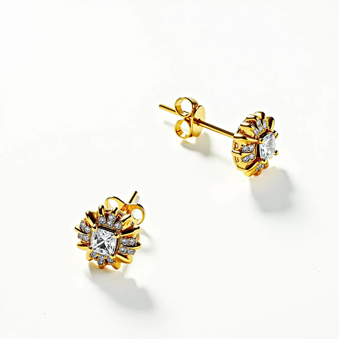 These moissanite earrings feature a central, square-cut moissanite gem, elegantly set in a classic prong setting that highlights its brilliance and clarity. Surrounding the central stone are smaller, round-cut moissanite stones, arranged in a floral pattern that adds a touch of sophistication to the design. The earrings are crafted from a lustrous yellow metal, likely gold, which complements the sparkling stones and adds warmth to the overall aesthetic. The secure post and butterfly back attachments ensure ease of wear while maintaining style and elegance.